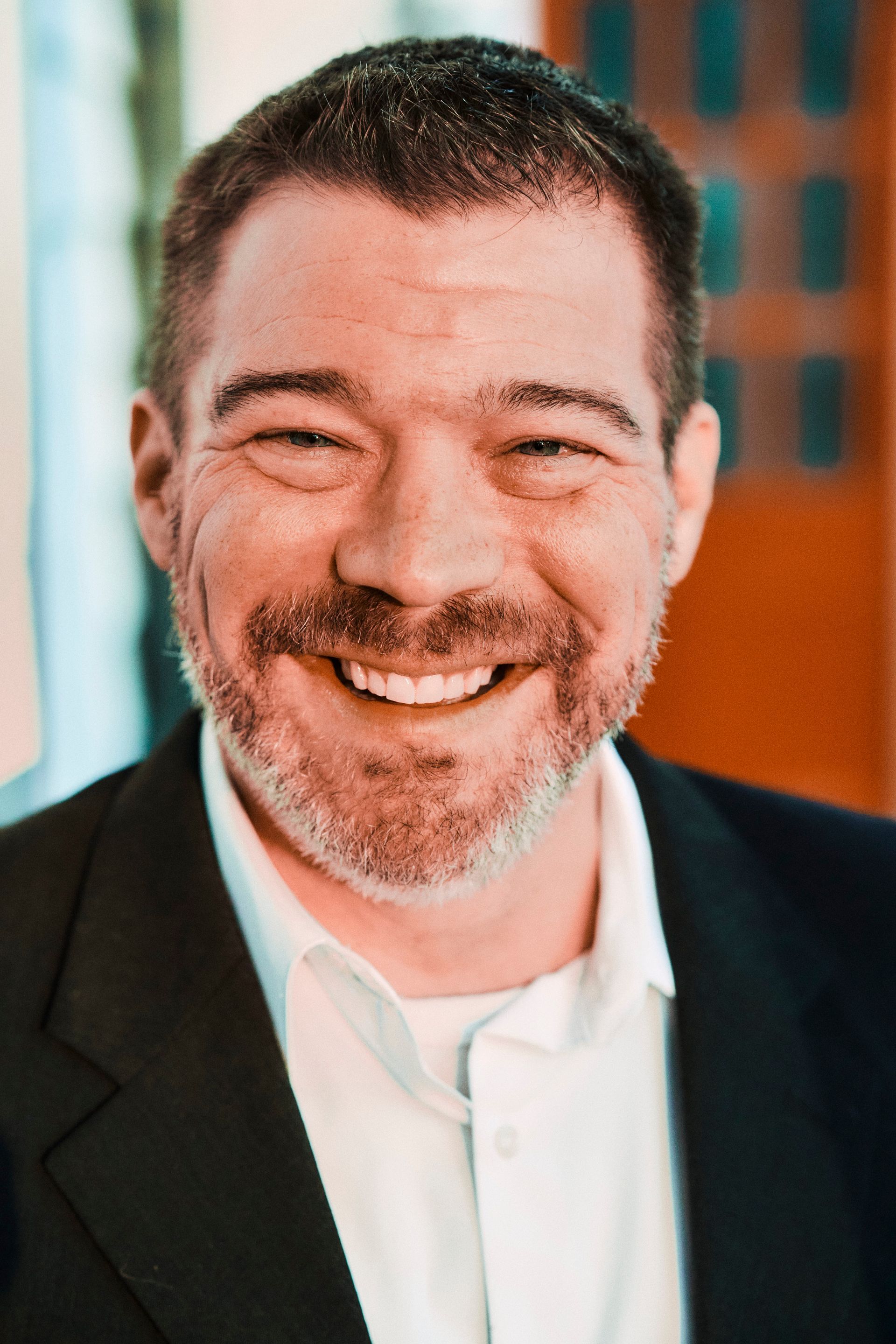 A man with a beard and a suit is smiling for the camera.