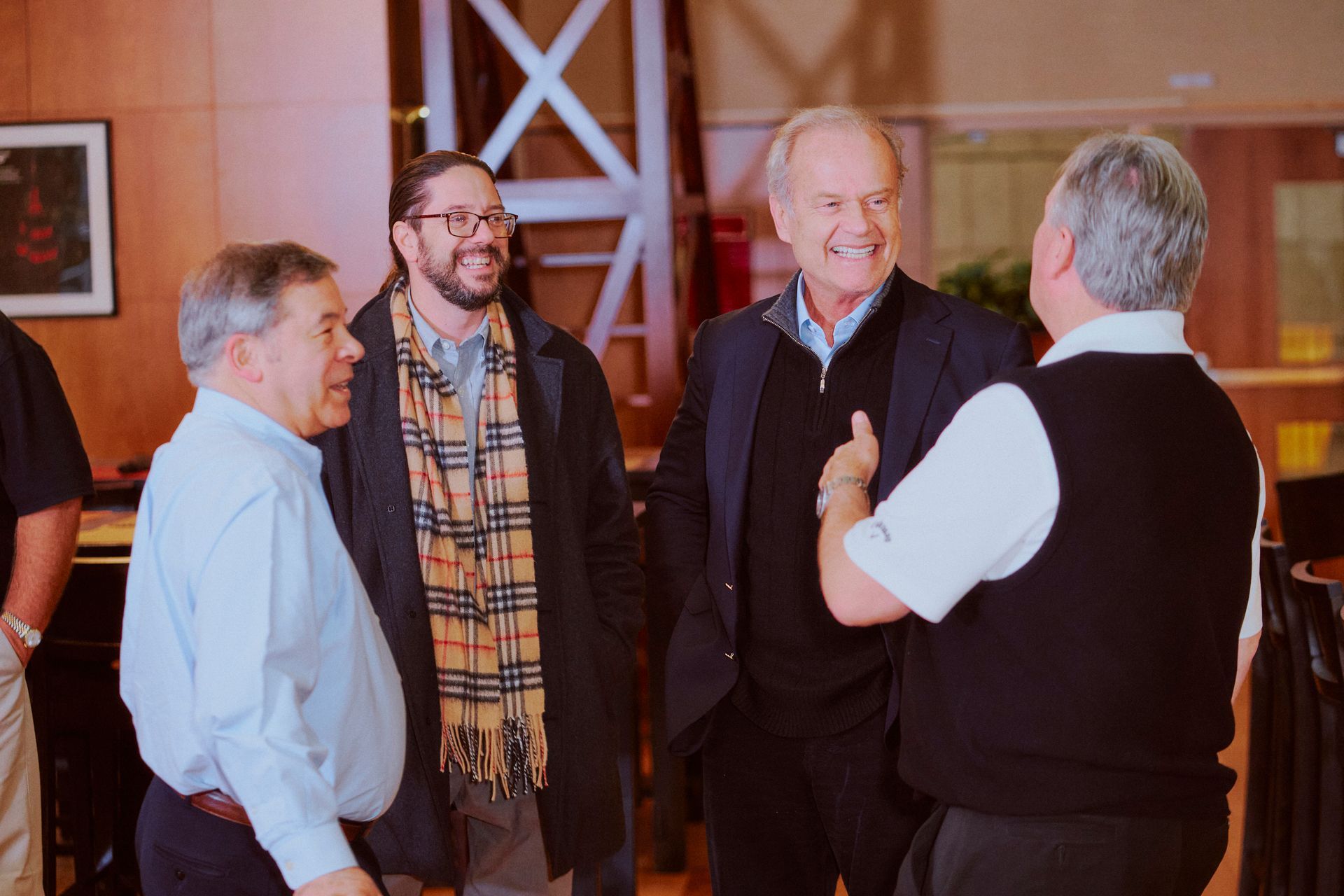A group of men are standing in a room talking to each other