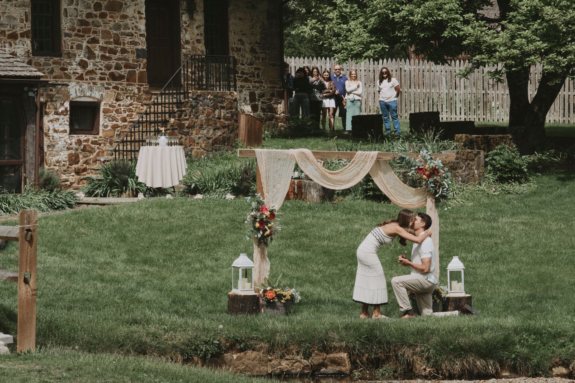 A man is proposing to a woman in front of a stone building.
