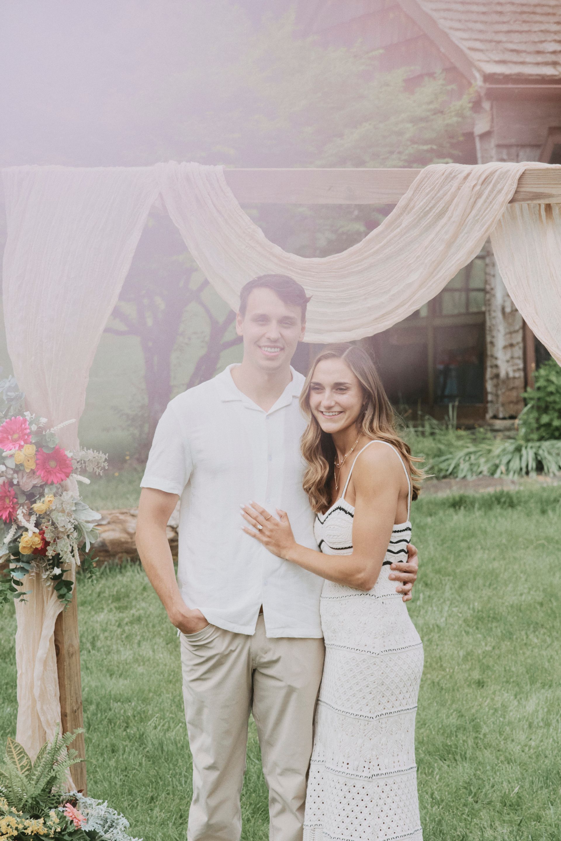 A man and a woman are posing for a picture in front of a gazebo.