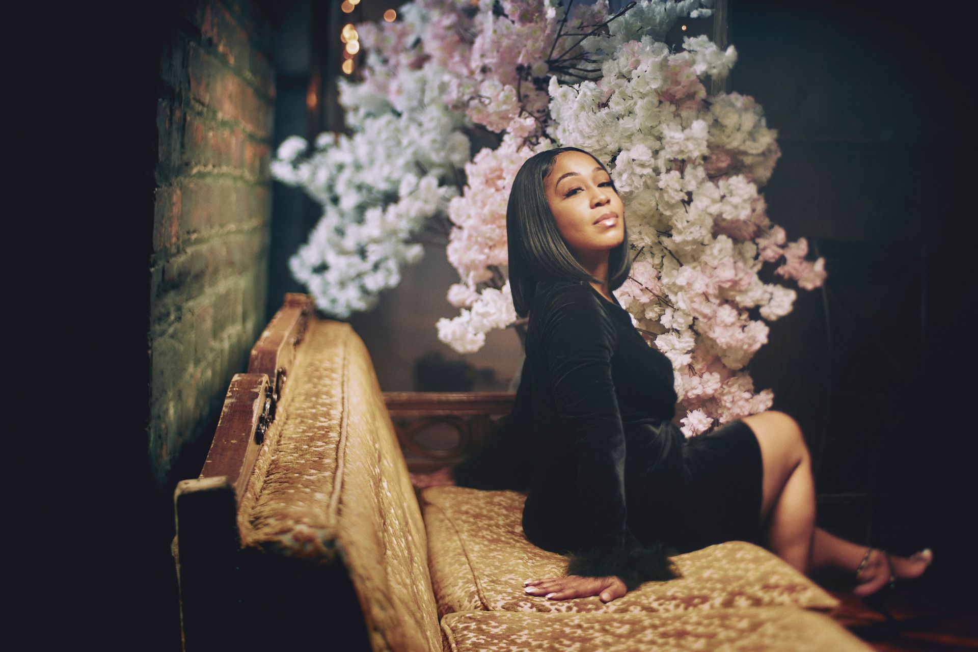 A woman is sitting on a couch in front of a cherry blossom tree.