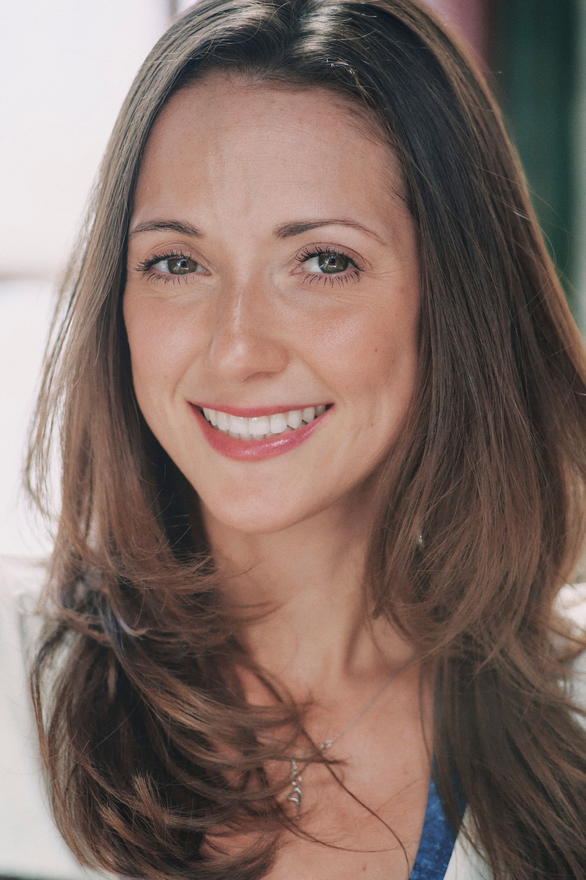 A woman with long brown hair is smiling for the camera.