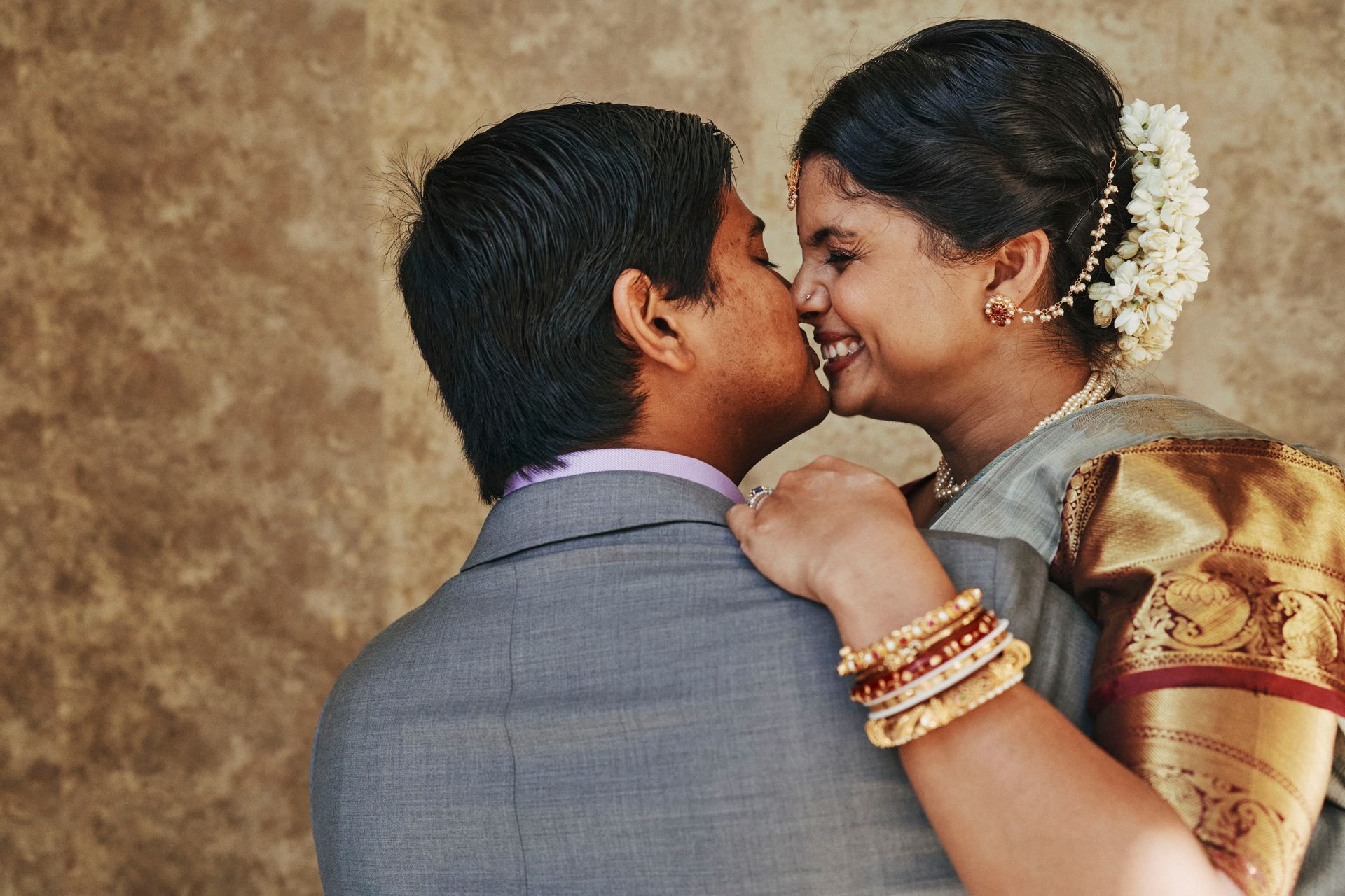 A man and woman are kissing and the woman has a flower in her hair