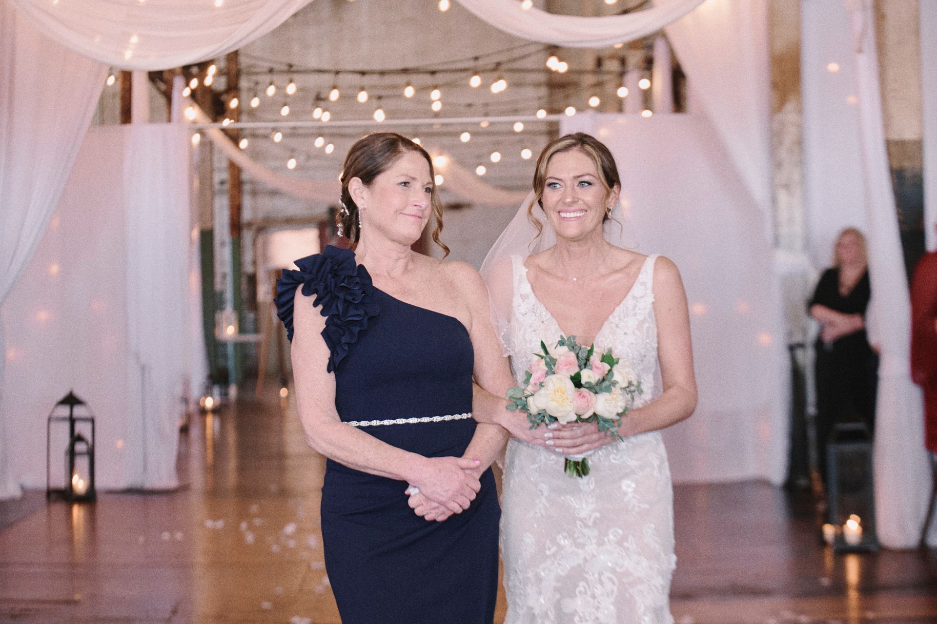 A bride and her mother are walking down the aisle at a wedding.