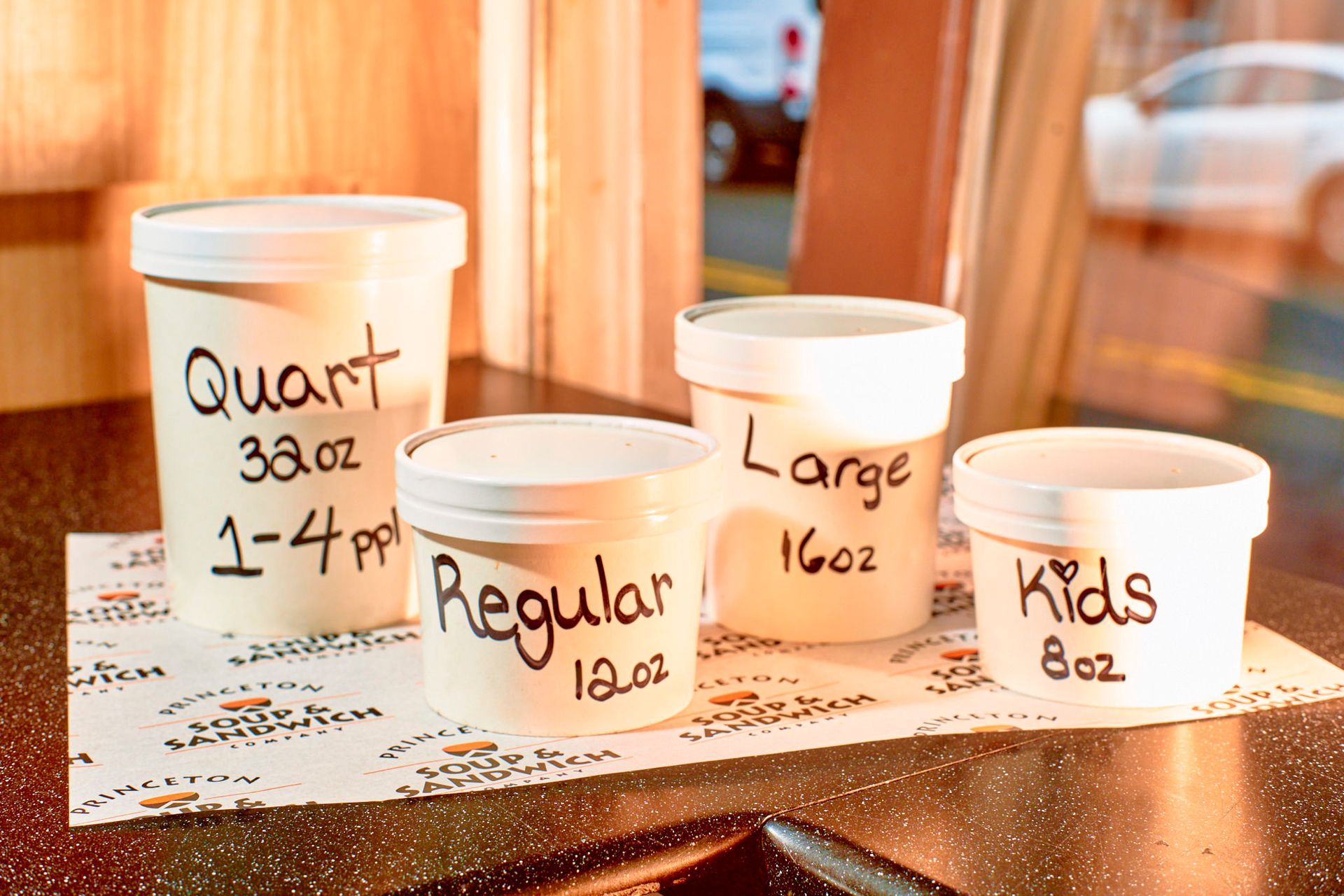 Four containers of ice cream: quart (32oz), large (16oz), regular (12oz), and kids (8oz) on a table.