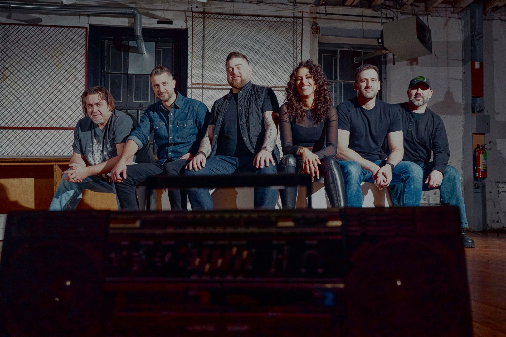 A group of people are sitting on a bench in a dark room.