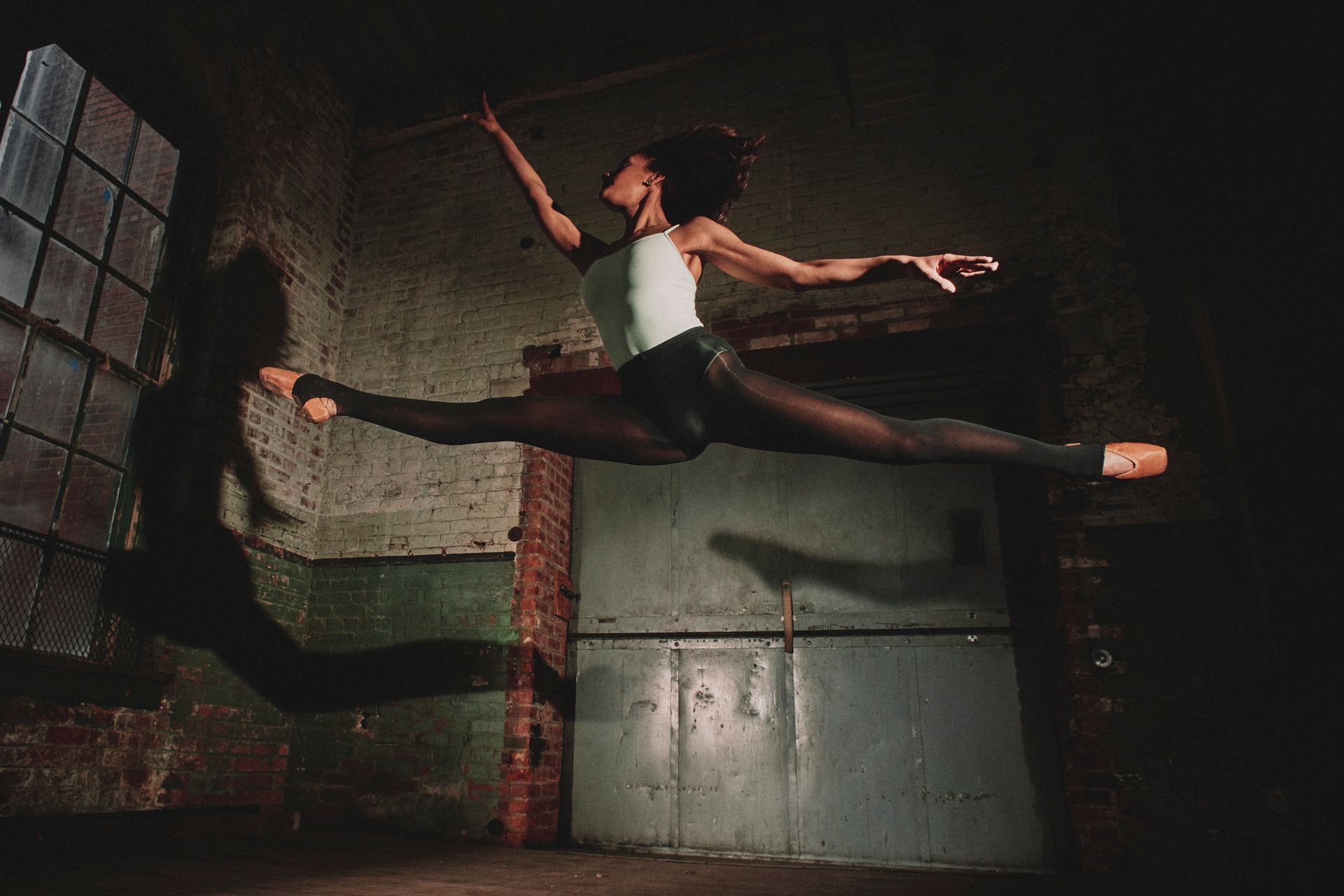 A woman is jumping in the air in a dark room.