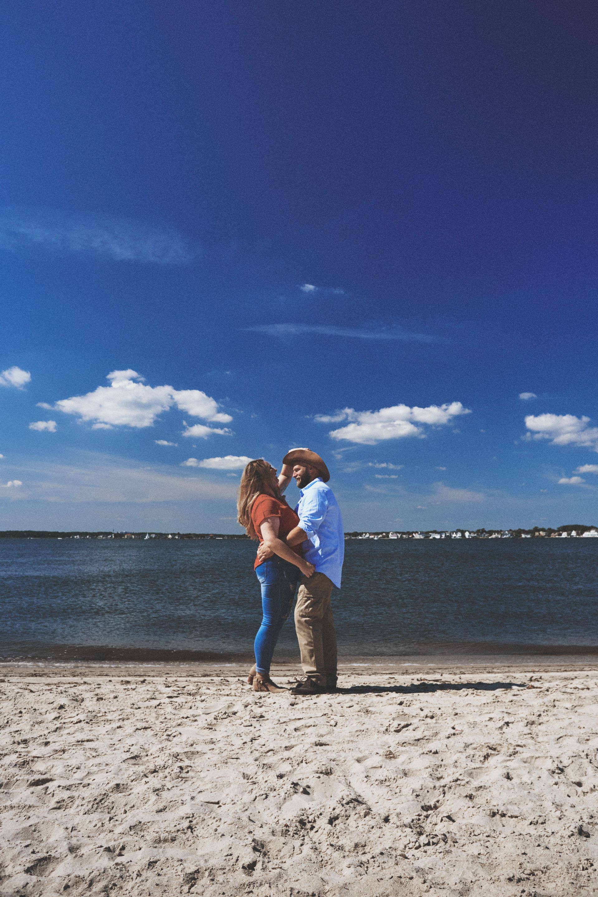 A man and a woman are kissing on the beach.