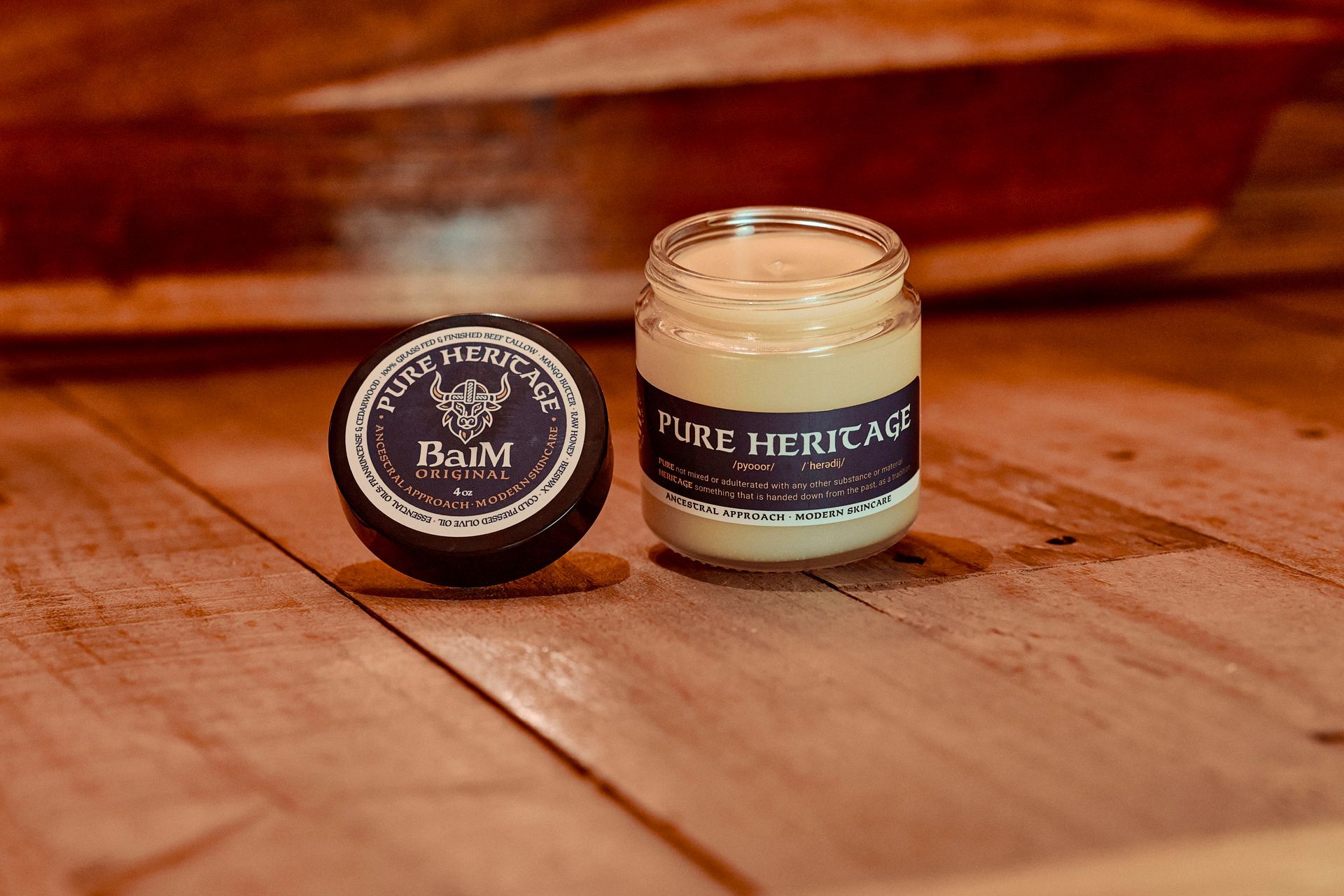 Two jars of product, one open, on a wooden surface. Both have dark blue labels with white text.
