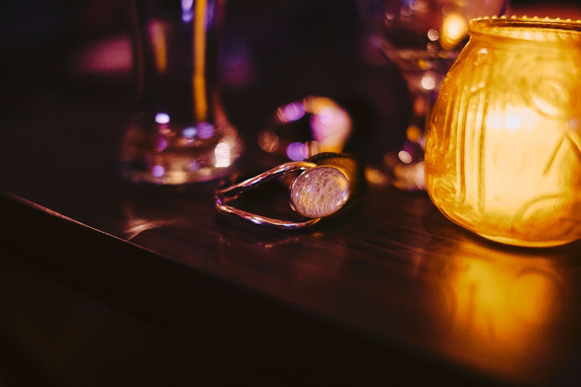 Champagne cork with wire cage on a dark surface, lit by a warm candle.