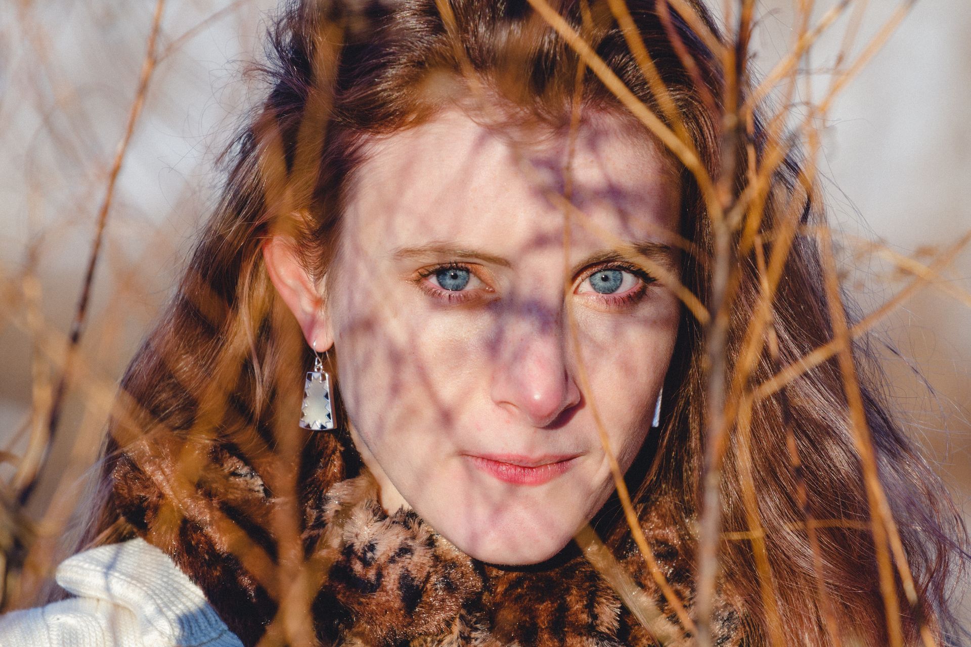 A close up of a woman 's face behind a tree branch.