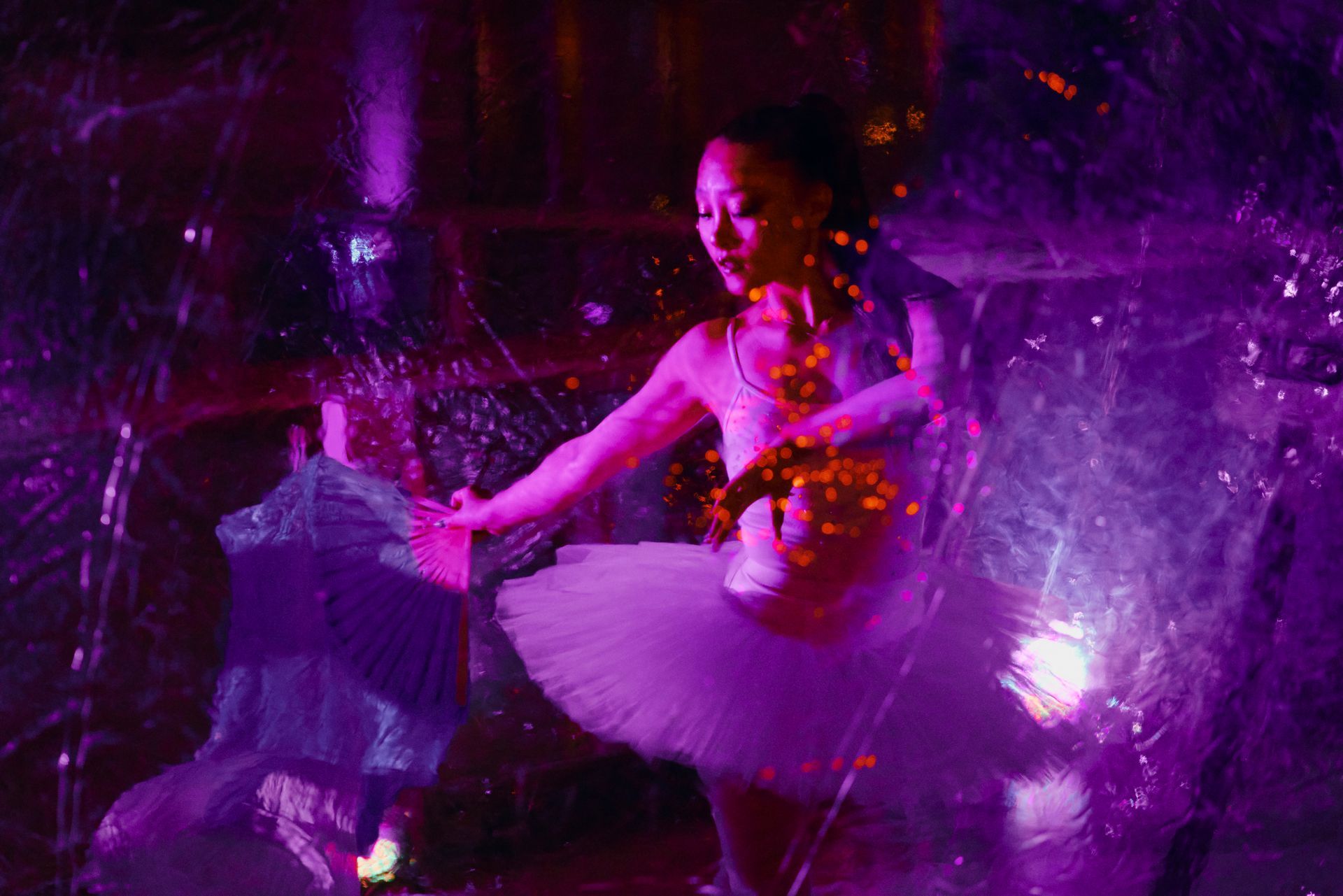 A ballerina in a tutu is dancing in a purple light.