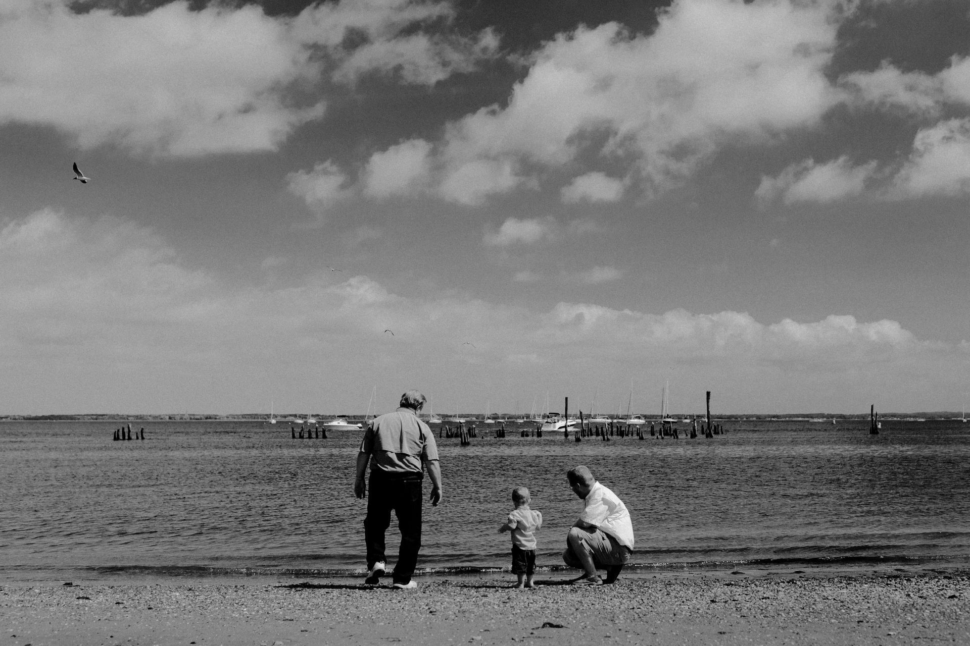 A black and white photo of two men and a child on a beach