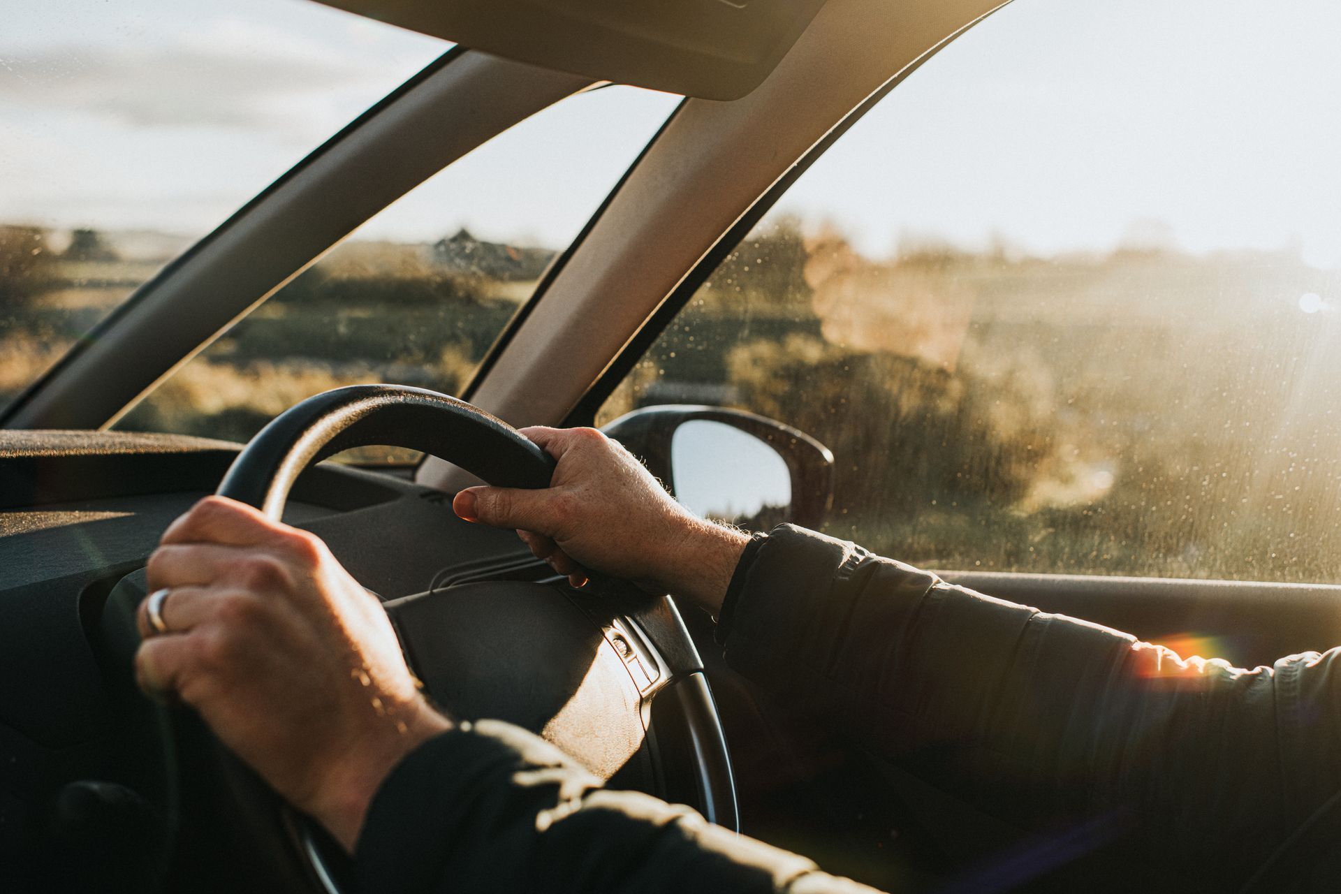 A person is driving a car with their hands on the steering wheel.