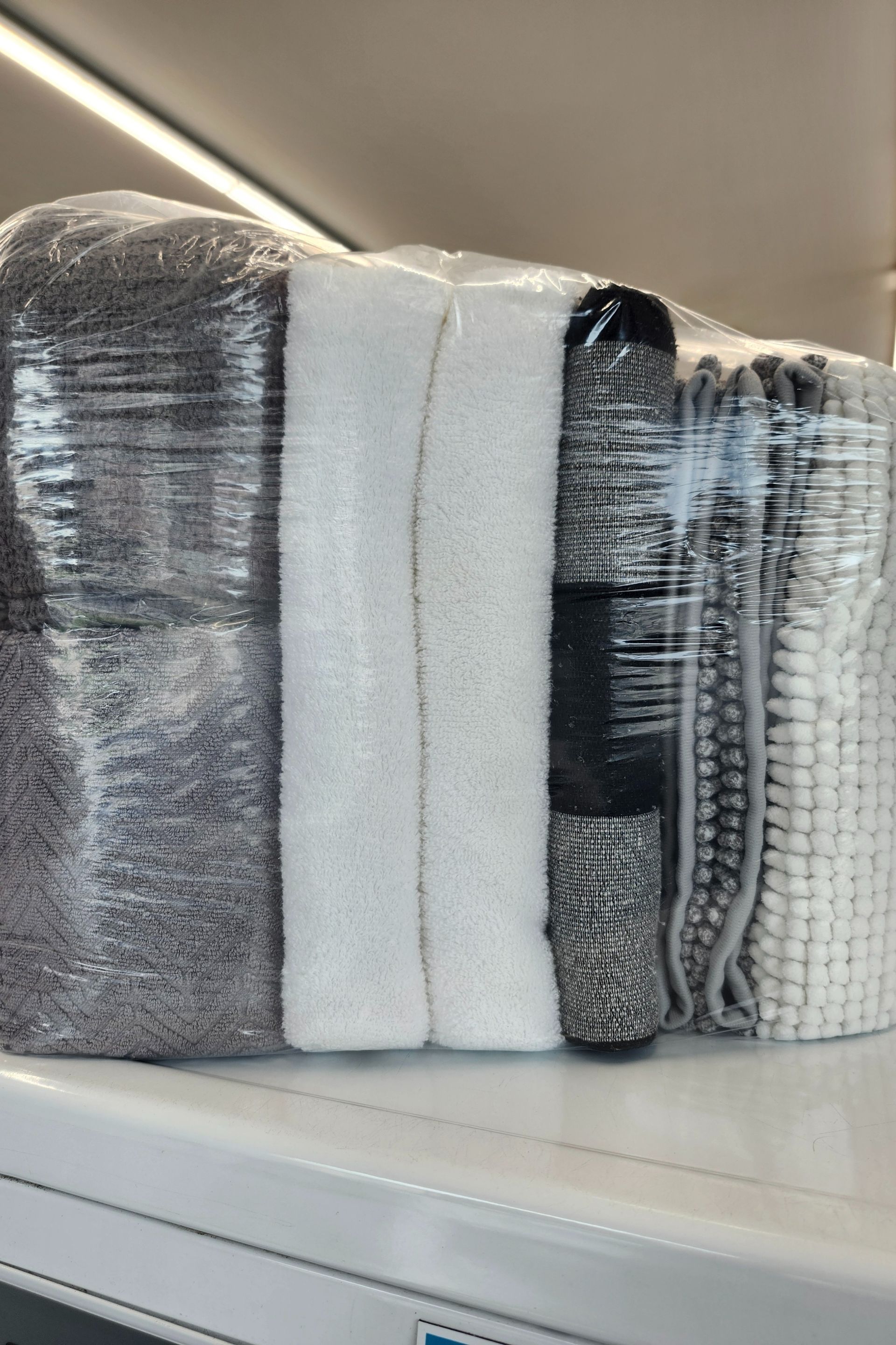 Folded gray, white, and black towels stacked on a shelf in a store aisle