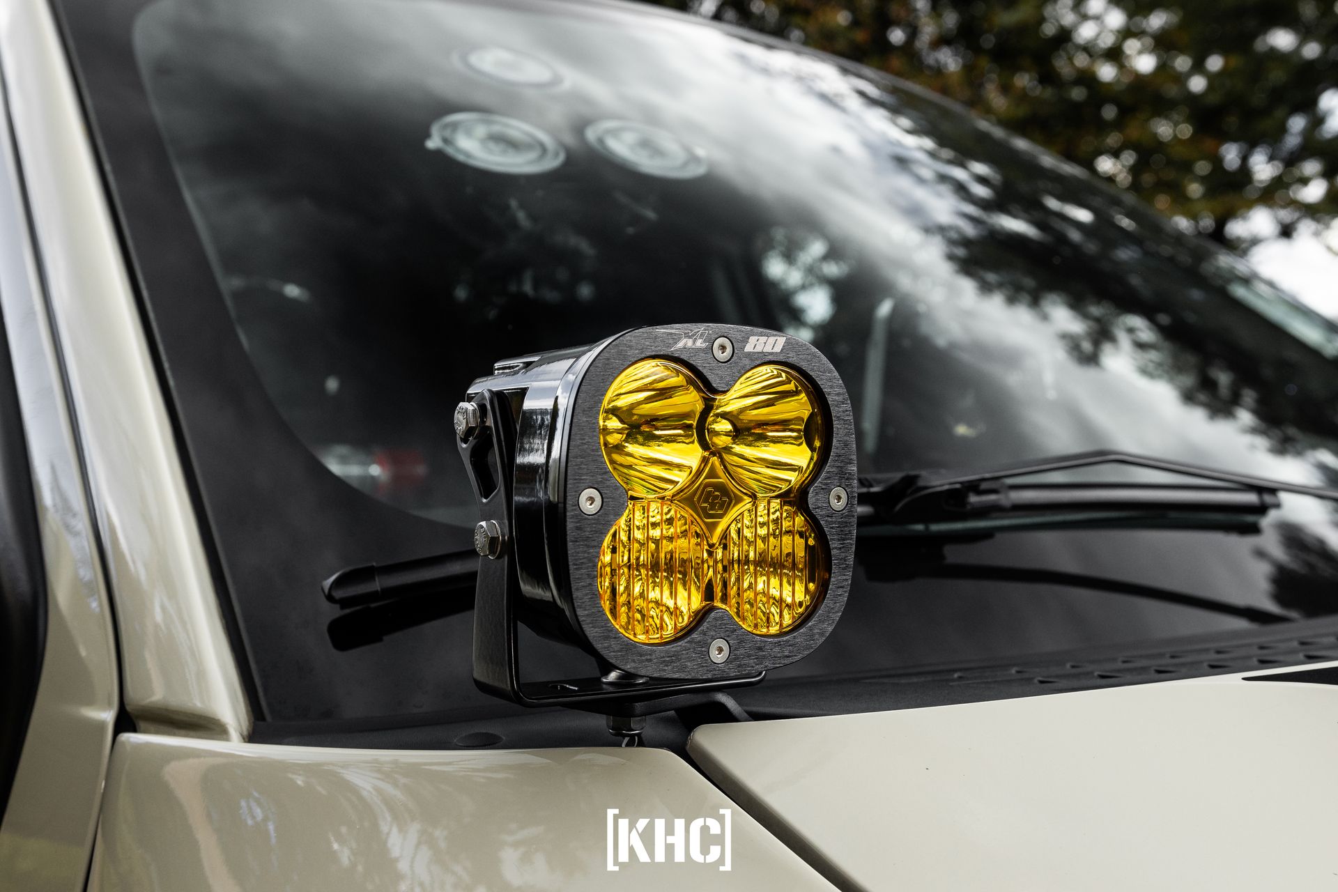 Yellow off-road light mounted on a vehicle's hood, next to the windshield.