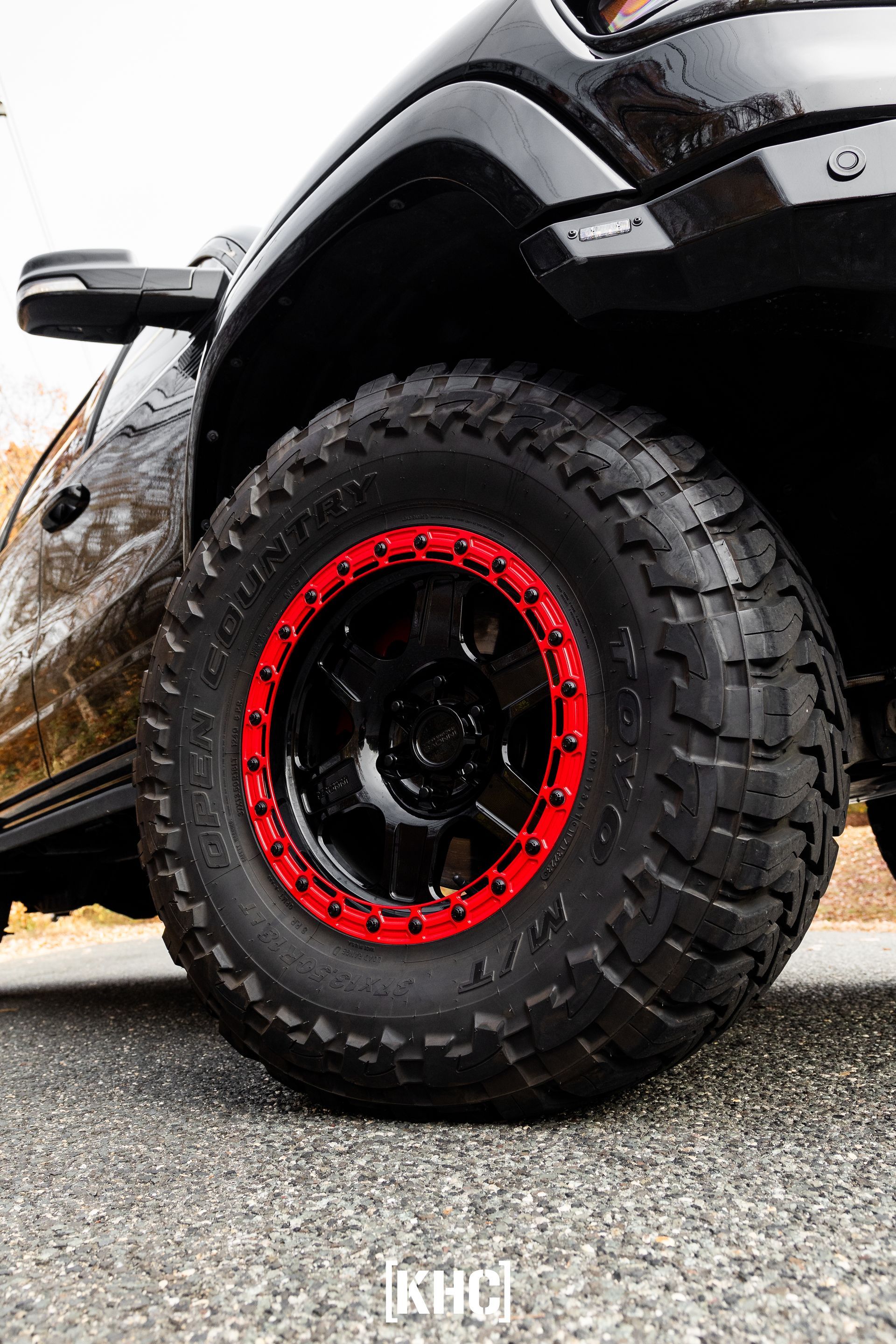 Black truck wheel with red rim. Rugged tire on asphalt.