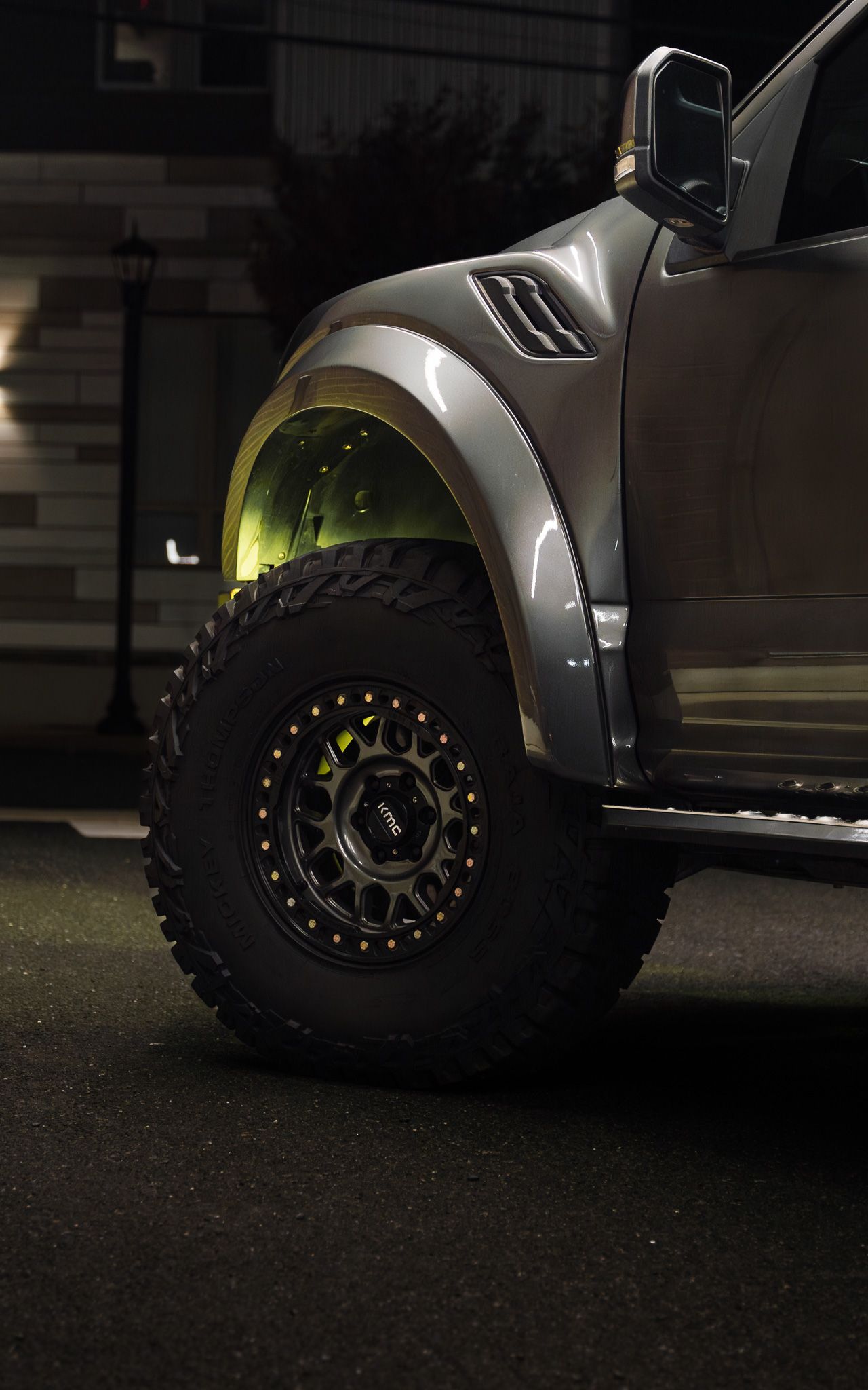 Gray truck tire with black rim. Yellow underglow visible in the wheel well.