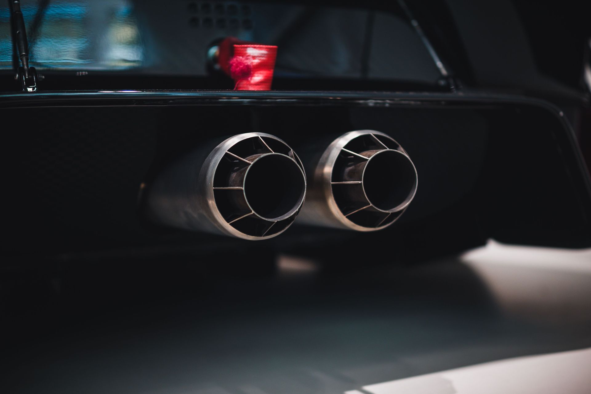 Rear view of a black high performance sports car with illuminated LED taillights in a modern garage.