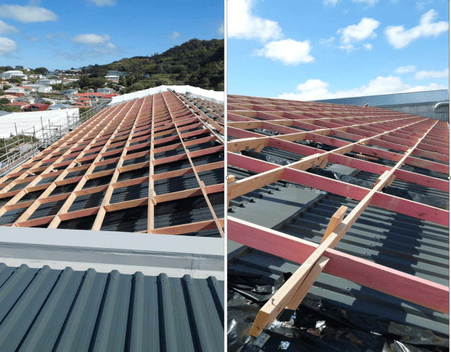 Roof under construction with red framing over gray metal panels and a blue sky in the background