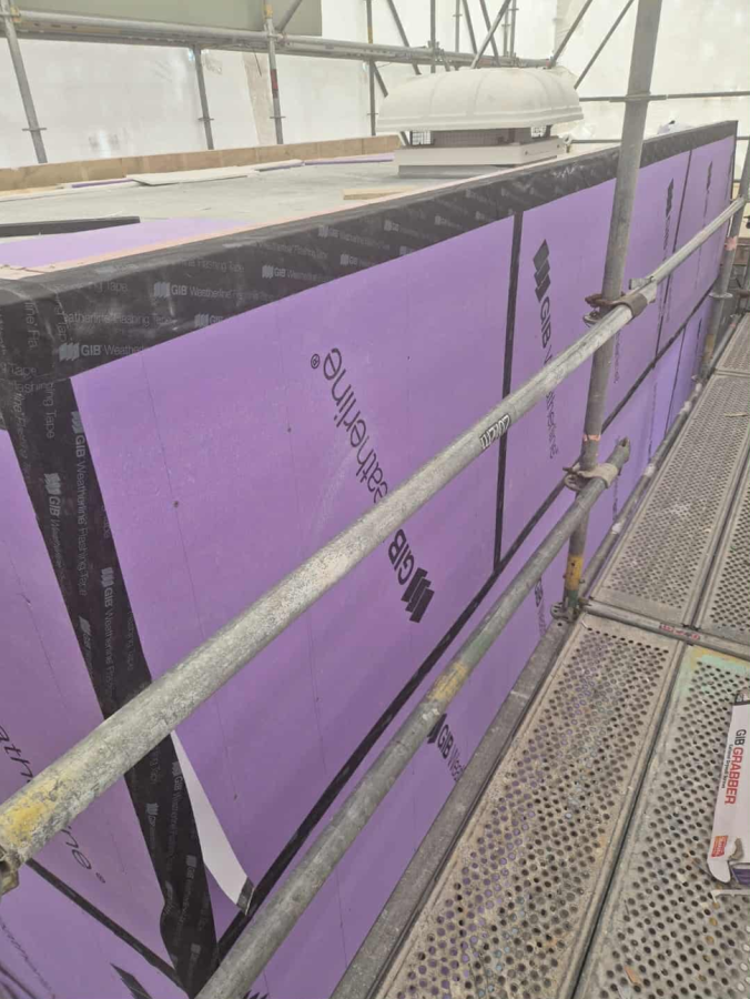 Purple insulation panels installed on scaffolding at a construction site