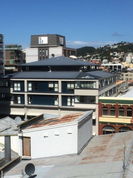 Urban waterfront buildings with blue-roofed structures under a clear sky.