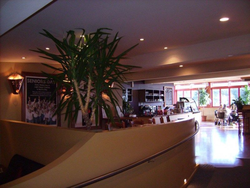 Hotel lobby with curved beige counter, potted plant, and bright seating area near windows