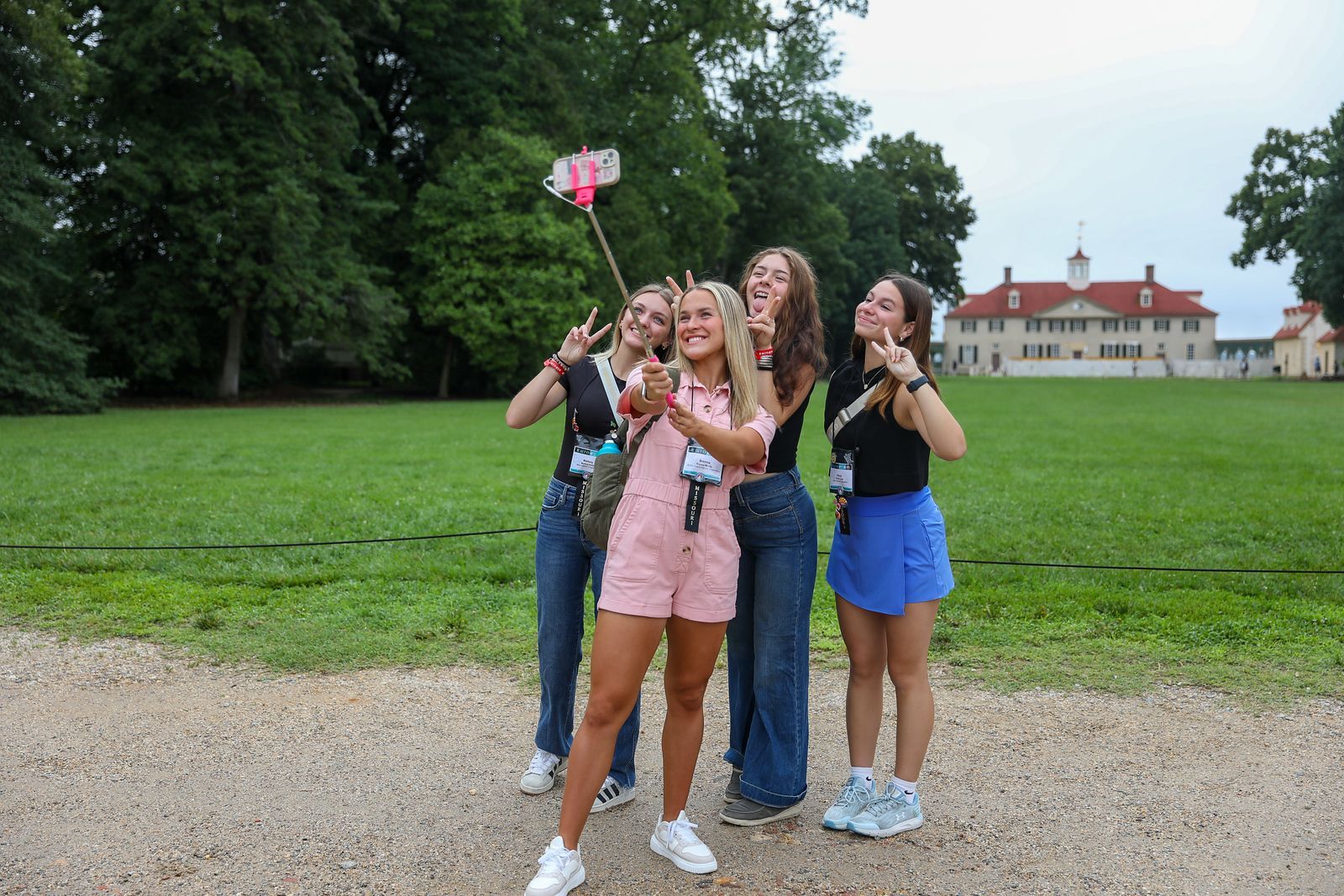 Four friends posing  in a grassy park, with a large building in the background