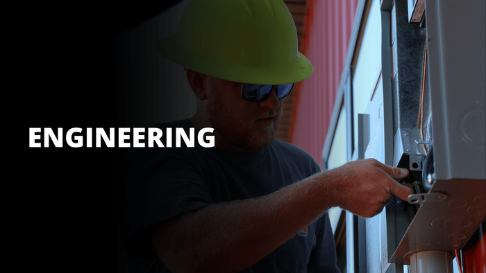Worker in a yellow hard hat installing wiring on a wall, with “ENGINEERING” text on the left.