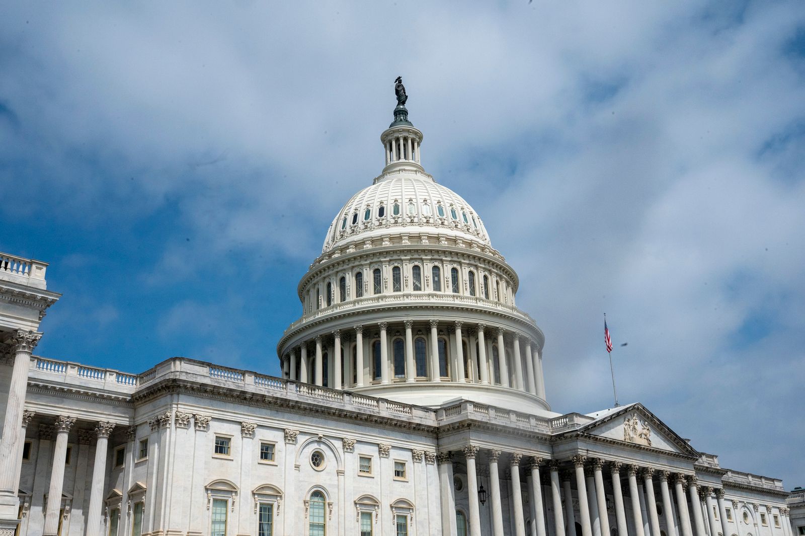 U.S. Capitol dome and facade under a partly cloudy blue sky