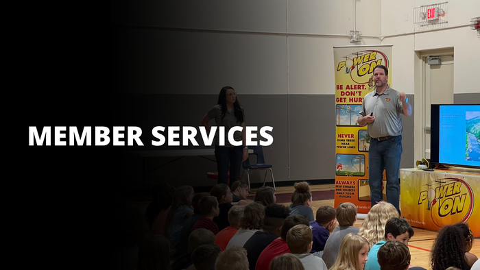 Member Services presentation in a room with an audience and a speaker beside a yellow banner