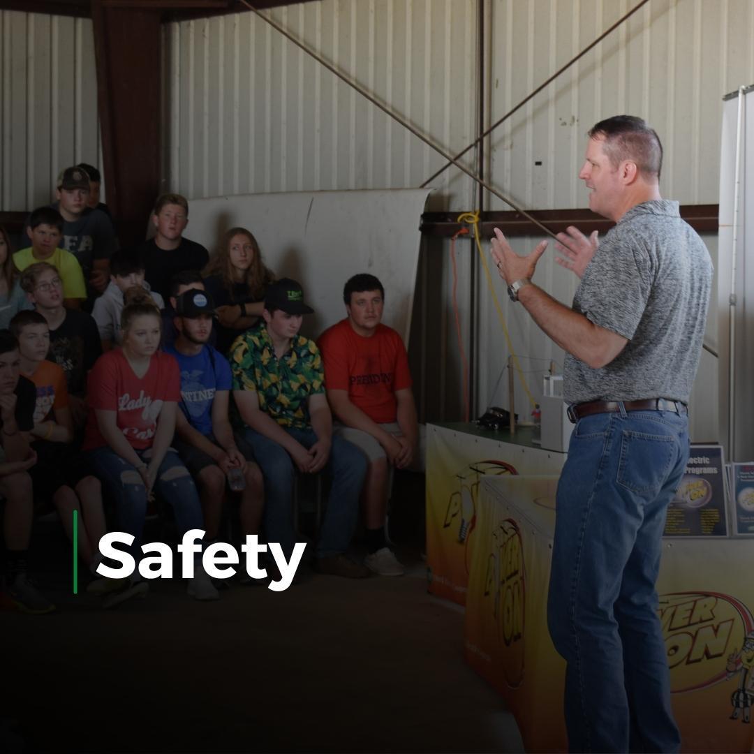 Speaker giving a safety talk to seated audience in a barn-like indoor setting