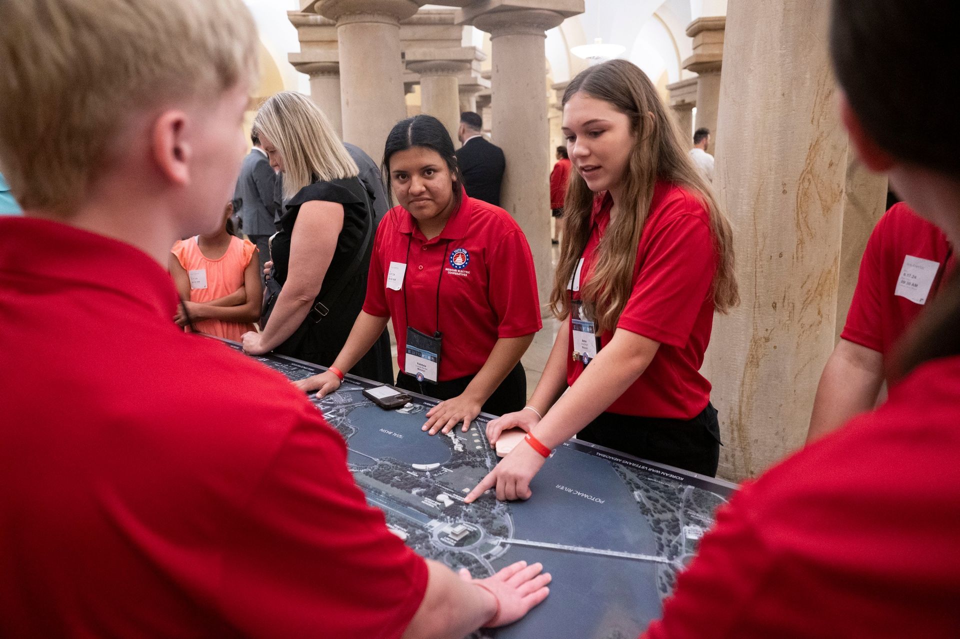 A group of people in red shirts are standing around a table.