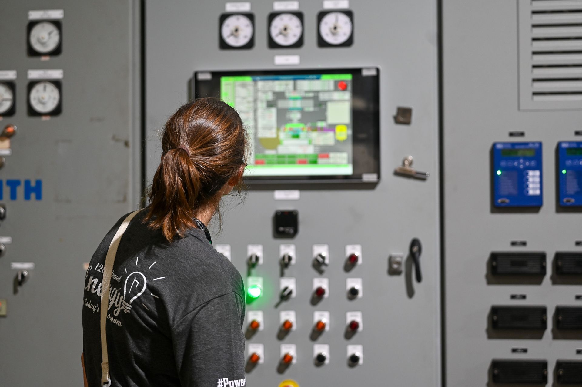 Teacher viewing a control panel monitor in an industrial electrical room