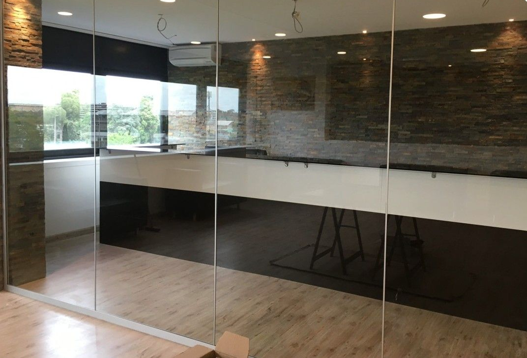 Interno di un moderno ufficio vuoto con pareti in vetro, pavimento in legno e bancone reception bianco e nero.