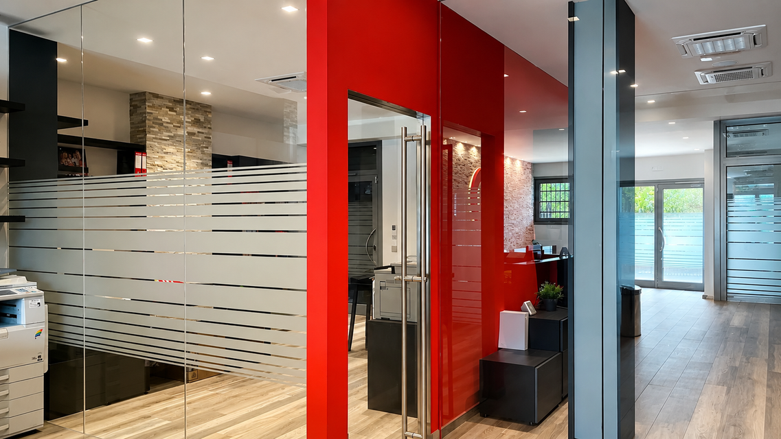 Hall di uffici moderna con parete decorativa rossa, divisori in vetro e pavimento in legno lucido.
