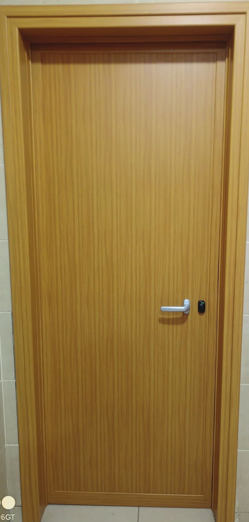 Porta interna chiusa in legno chiaro con maniglia argentata e piccola serratura.