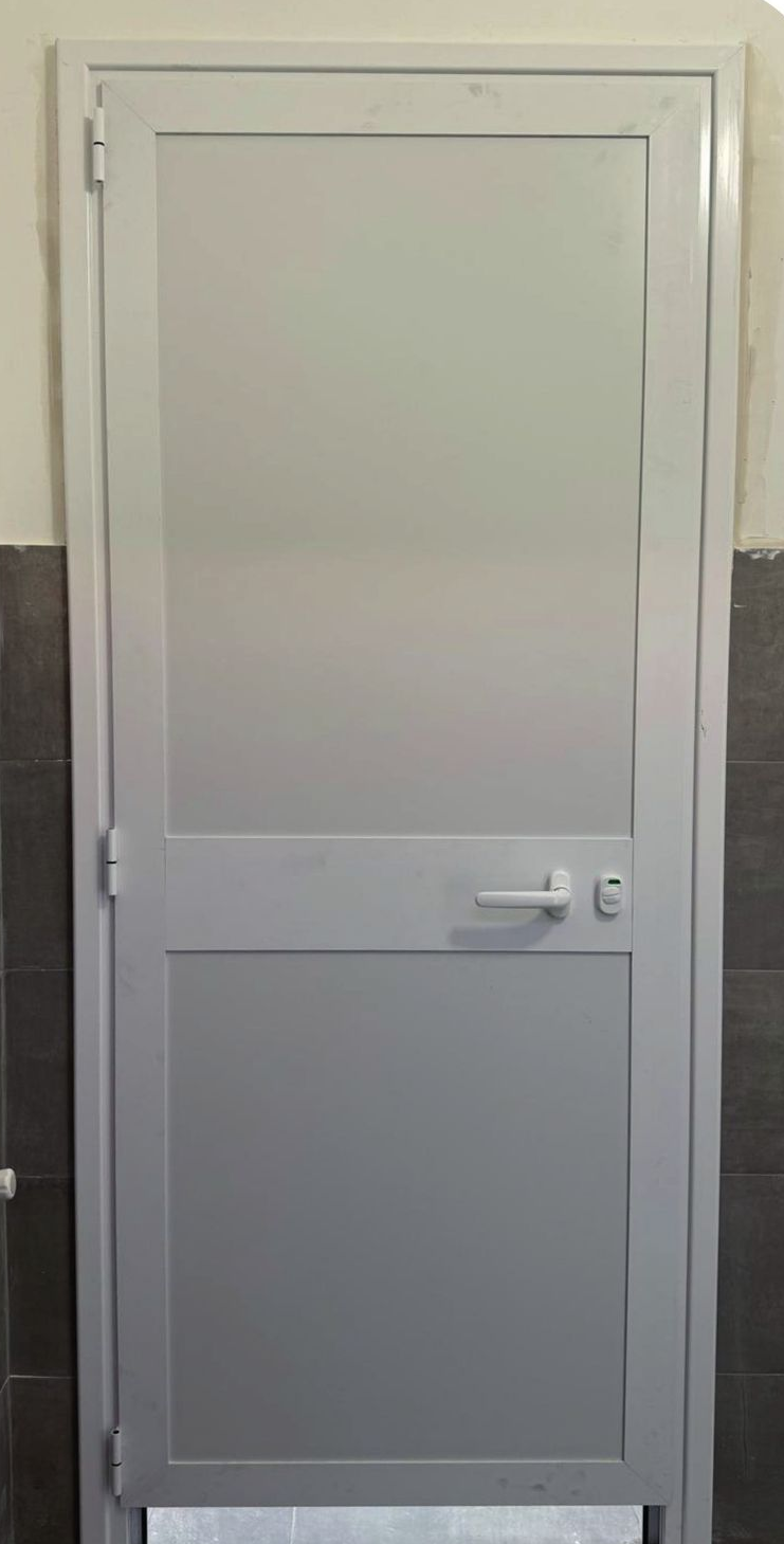 Porta metallica grigia con maniglia e serratura, incassata in un muro.