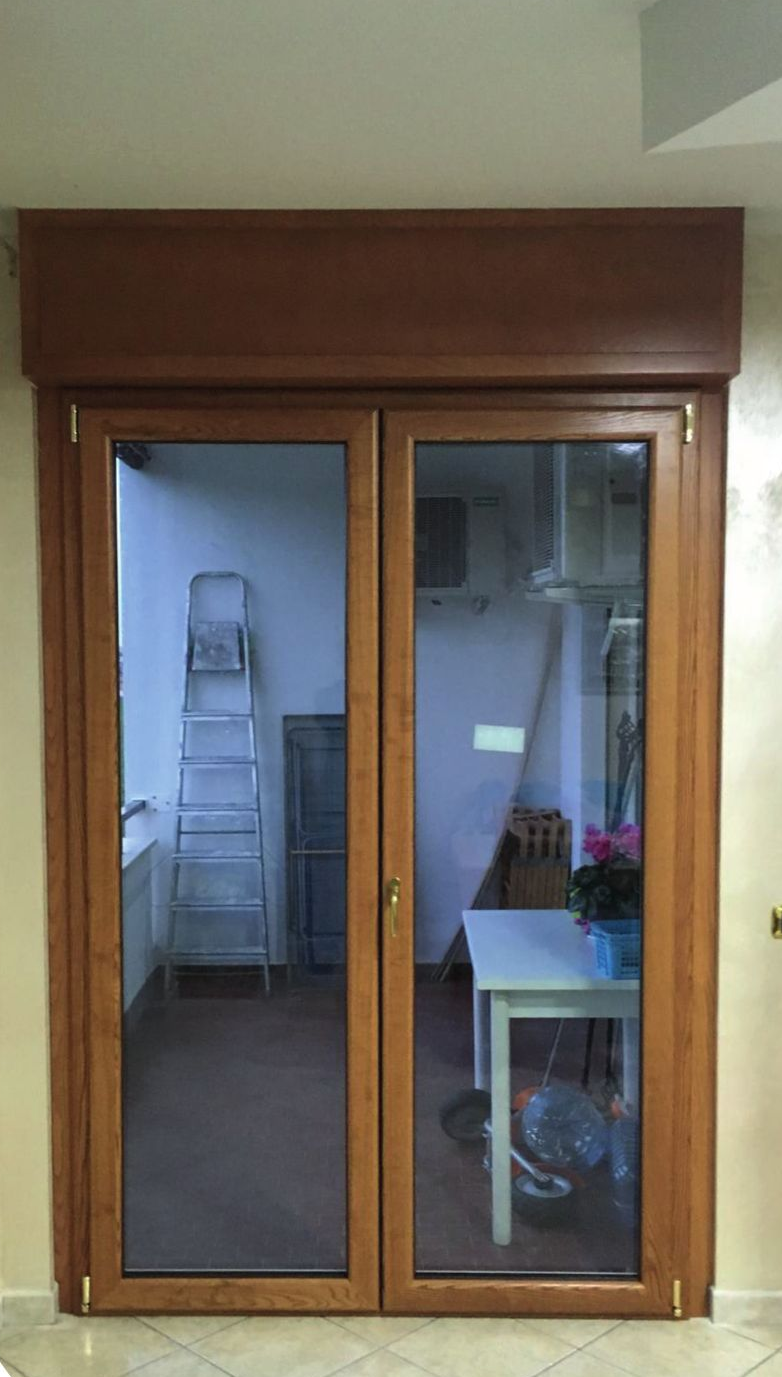 Doppie porte a vetri con telaio in legno chiuse che conducono a una stanza, all'interno della quale è visibile una scala.