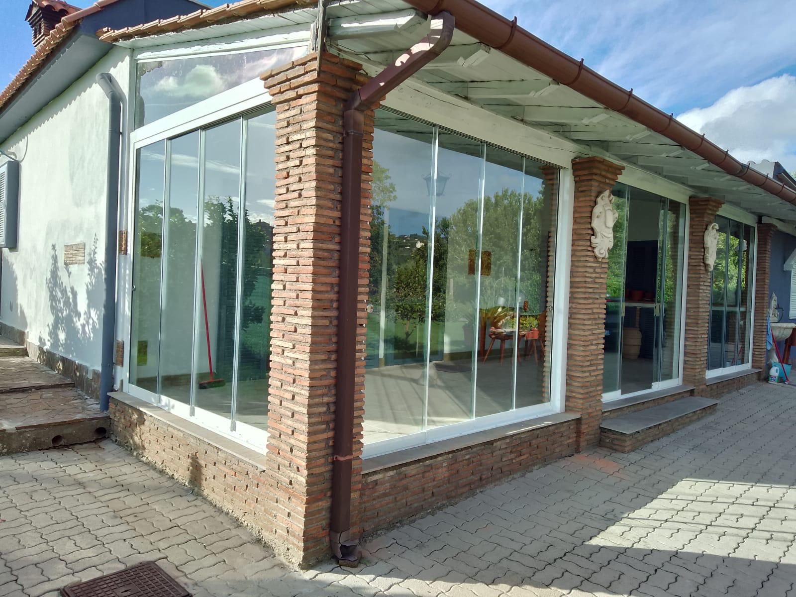 Negozio in mattoni con facciata in vetro, ampie finestre e ingresso pavimentato sotto un tetto spiovente.