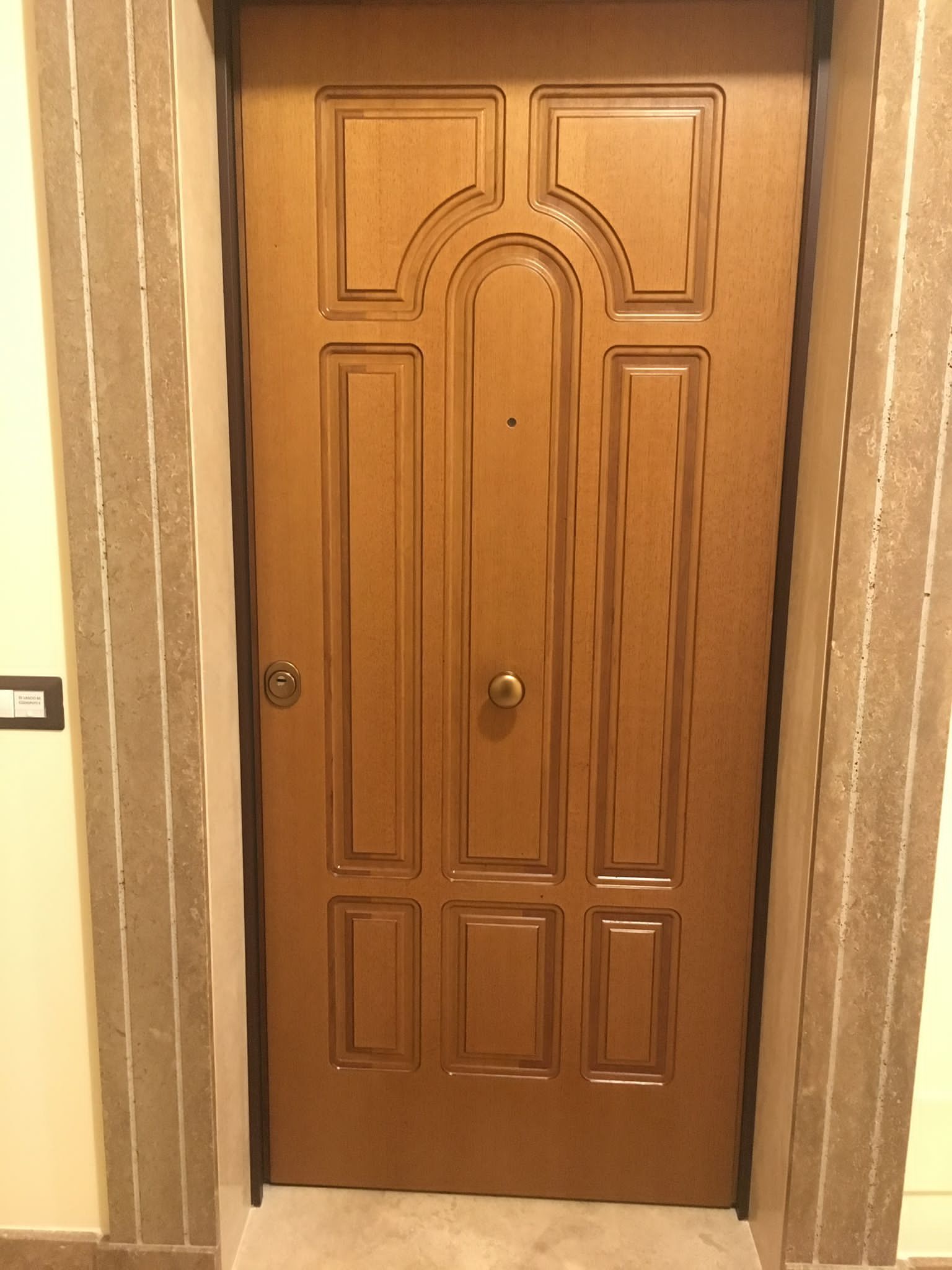 Porta d'appartamento con pannelli in legno in un corridoio beige