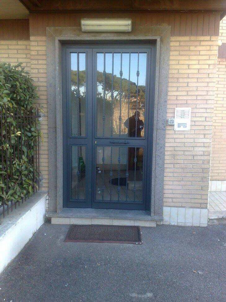 Ingresso principale con porta blu in metallo e vetro, muri in mattoni e un piccolo zerbino.
