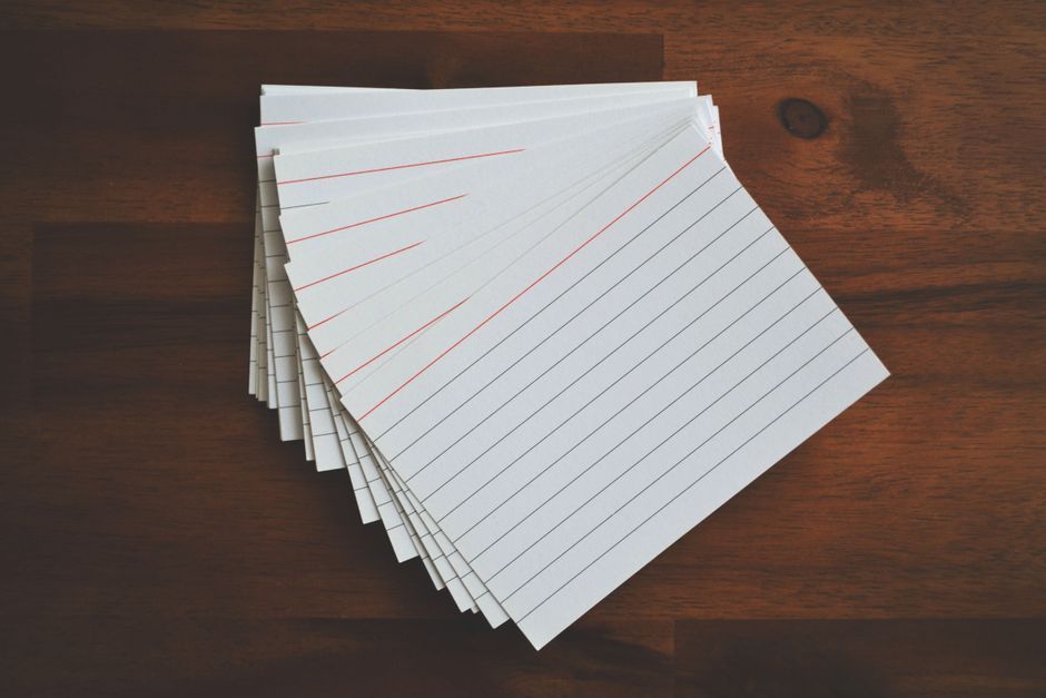 Open notebook, index cards, and a pen arranged on a light desk