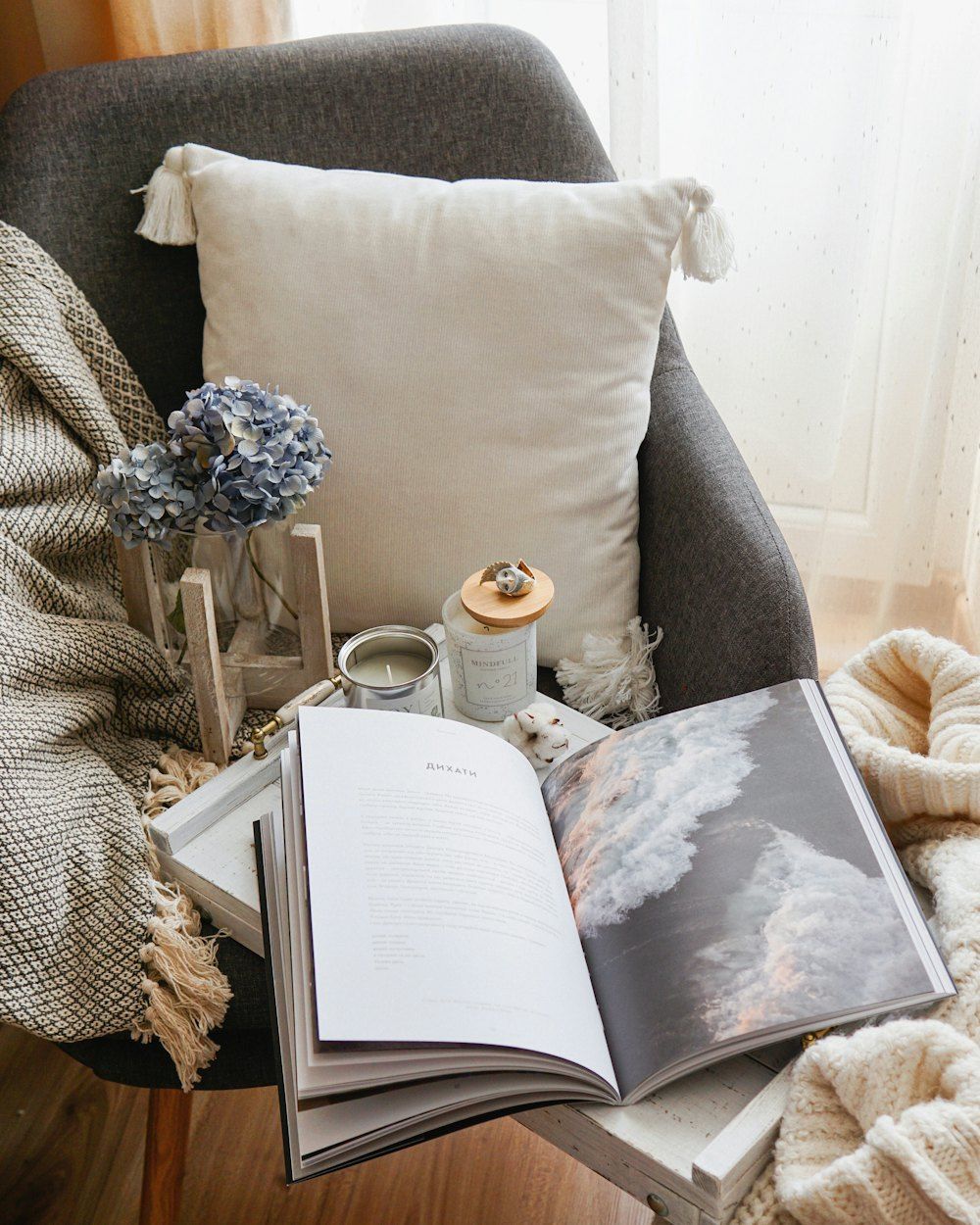 Open book resting beside a throw pillow in a cozy grey reading nook