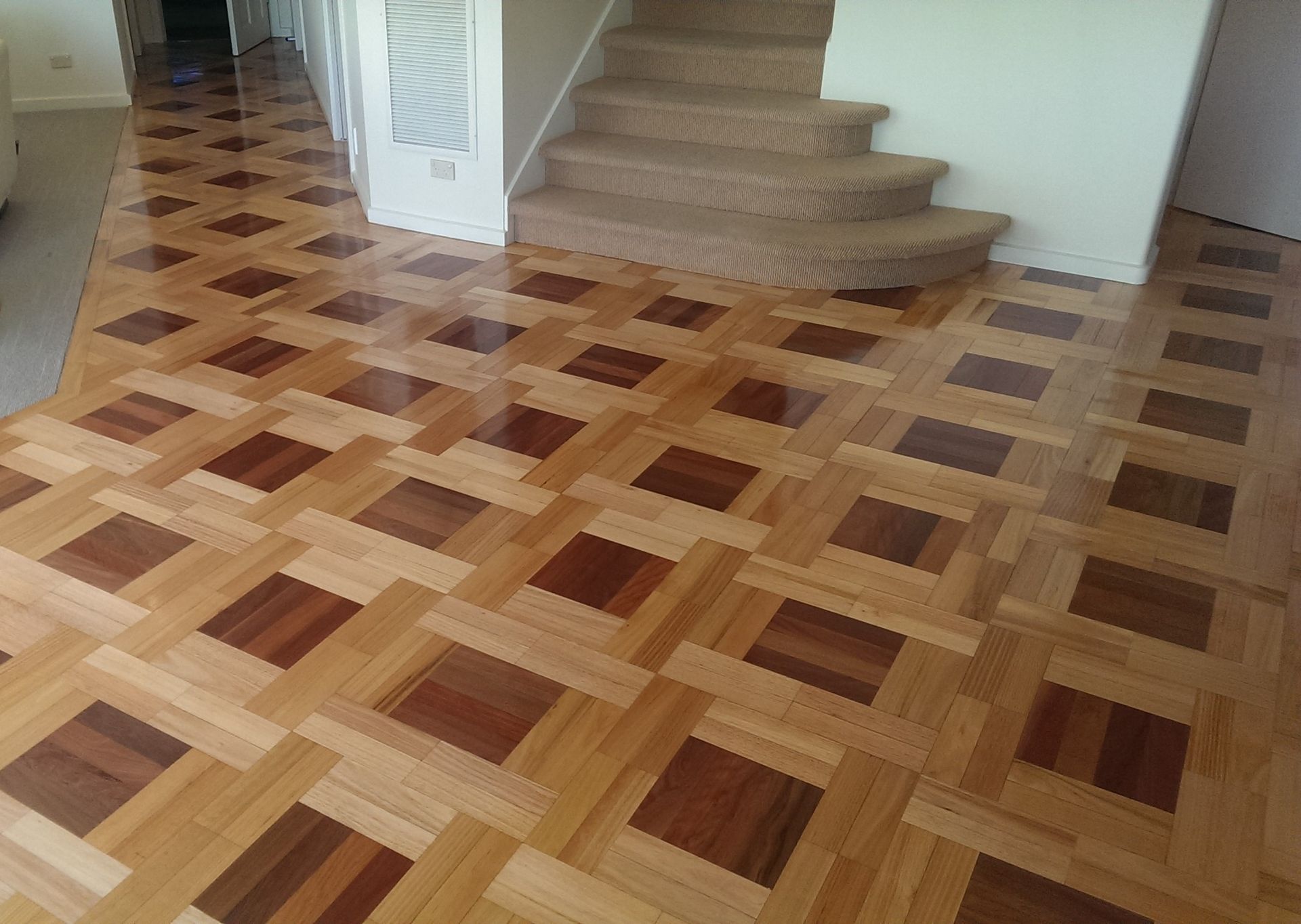 An empty room with hardwood floors and two windows.