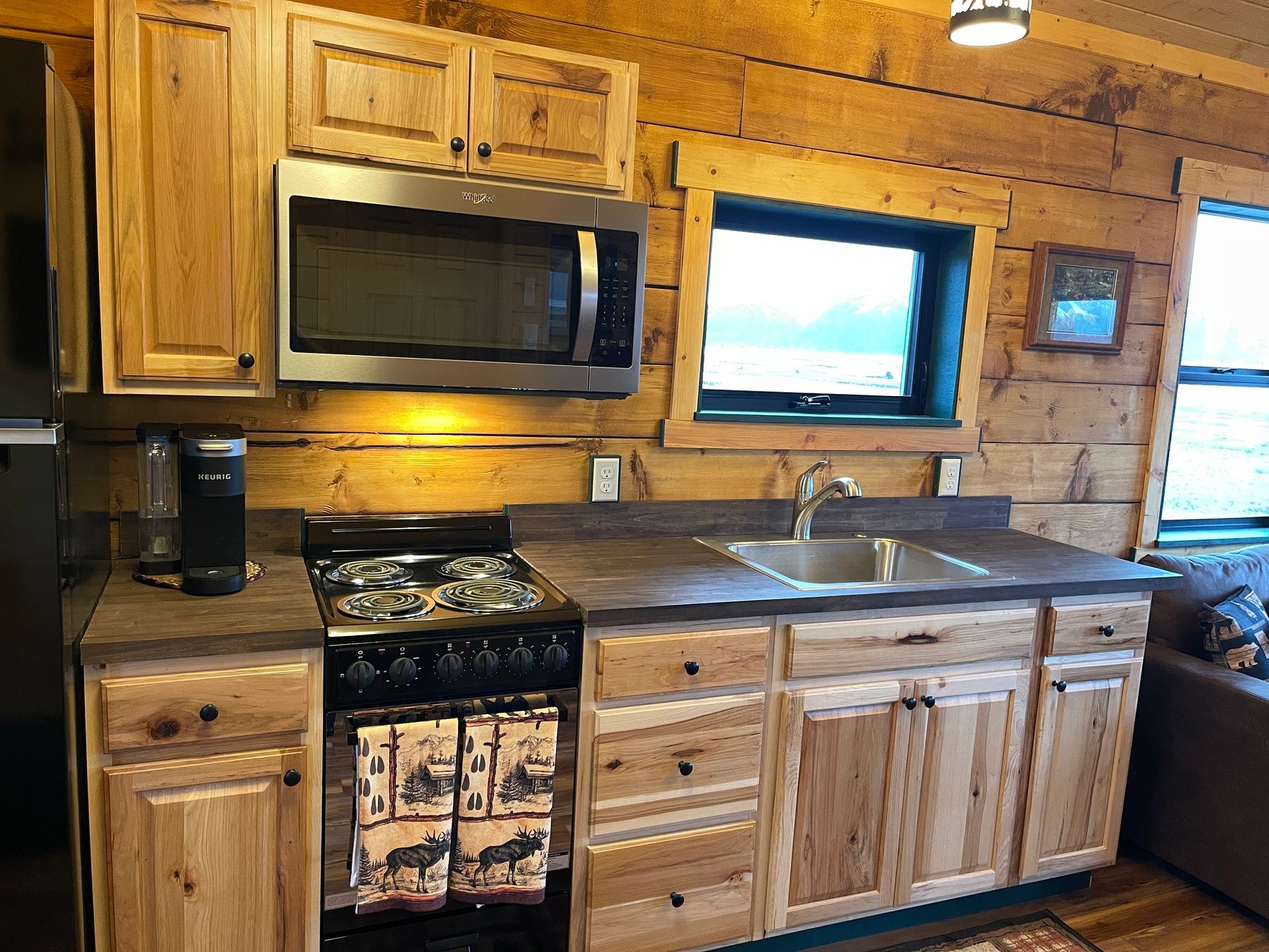 A kitchen in a log cabin with stainless steel appliances and wooden cabinets.