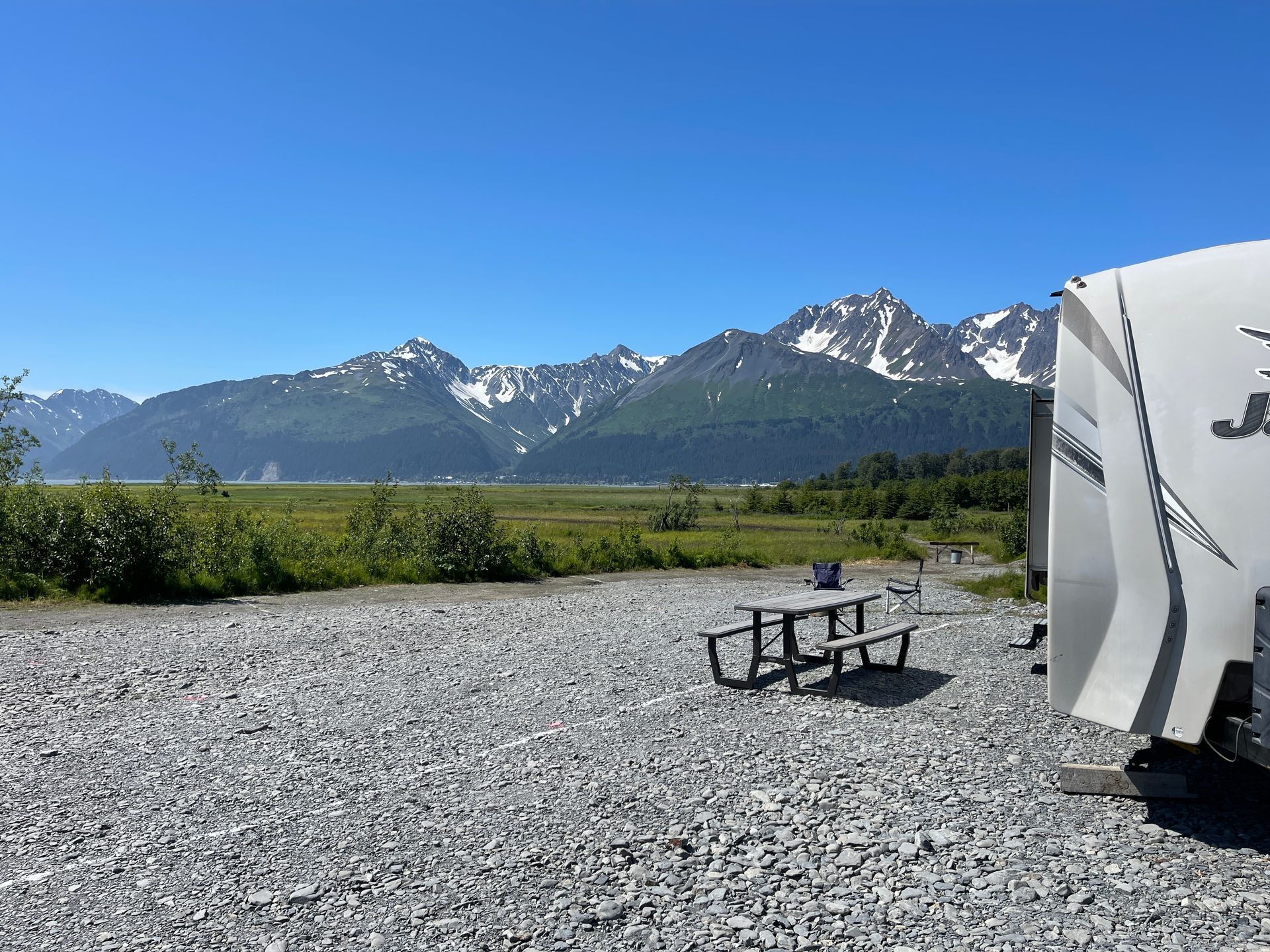 A man is kneeling down next to a camper.