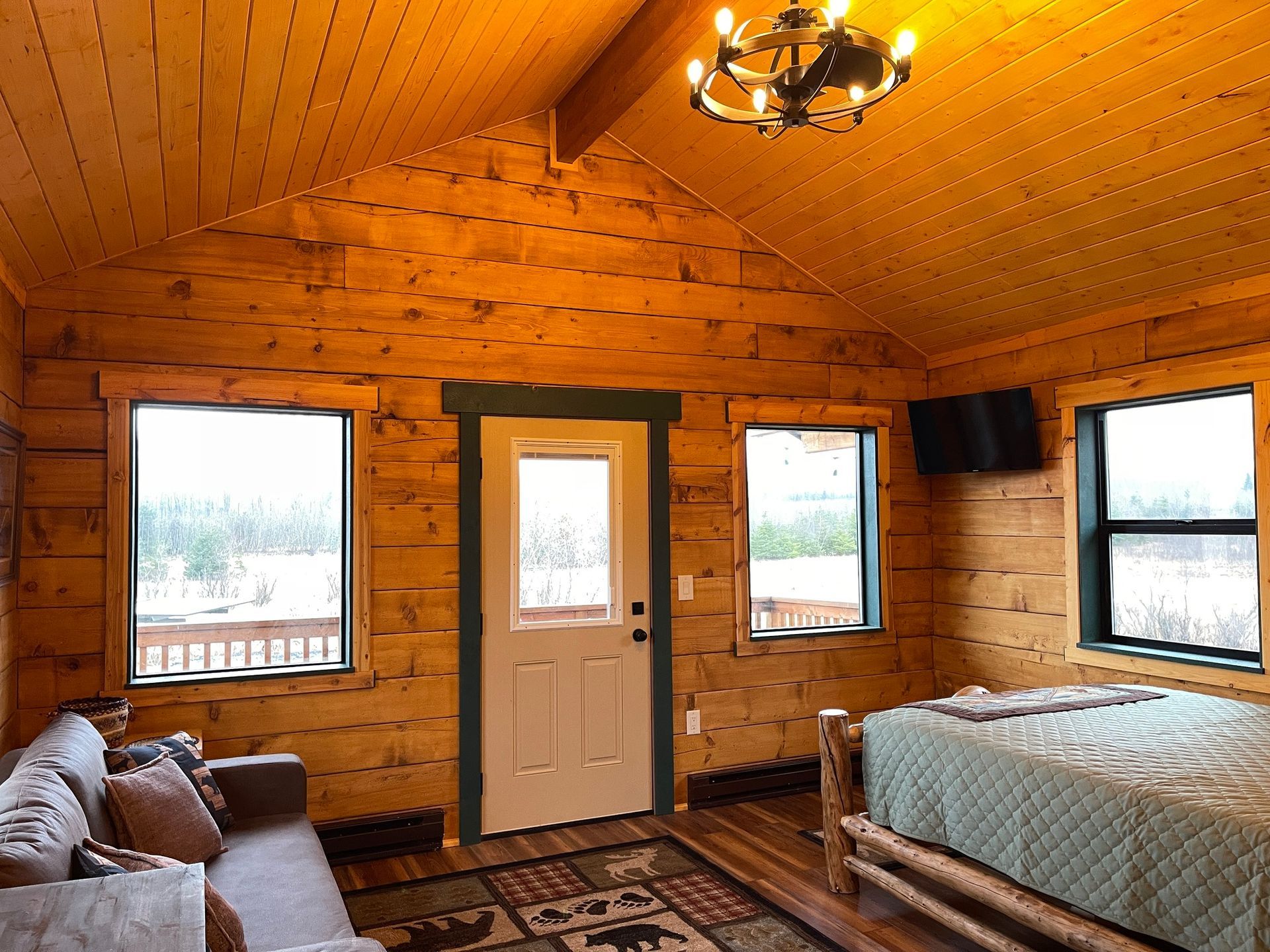 A bedroom in a log cabin with a bed , couch , and television.