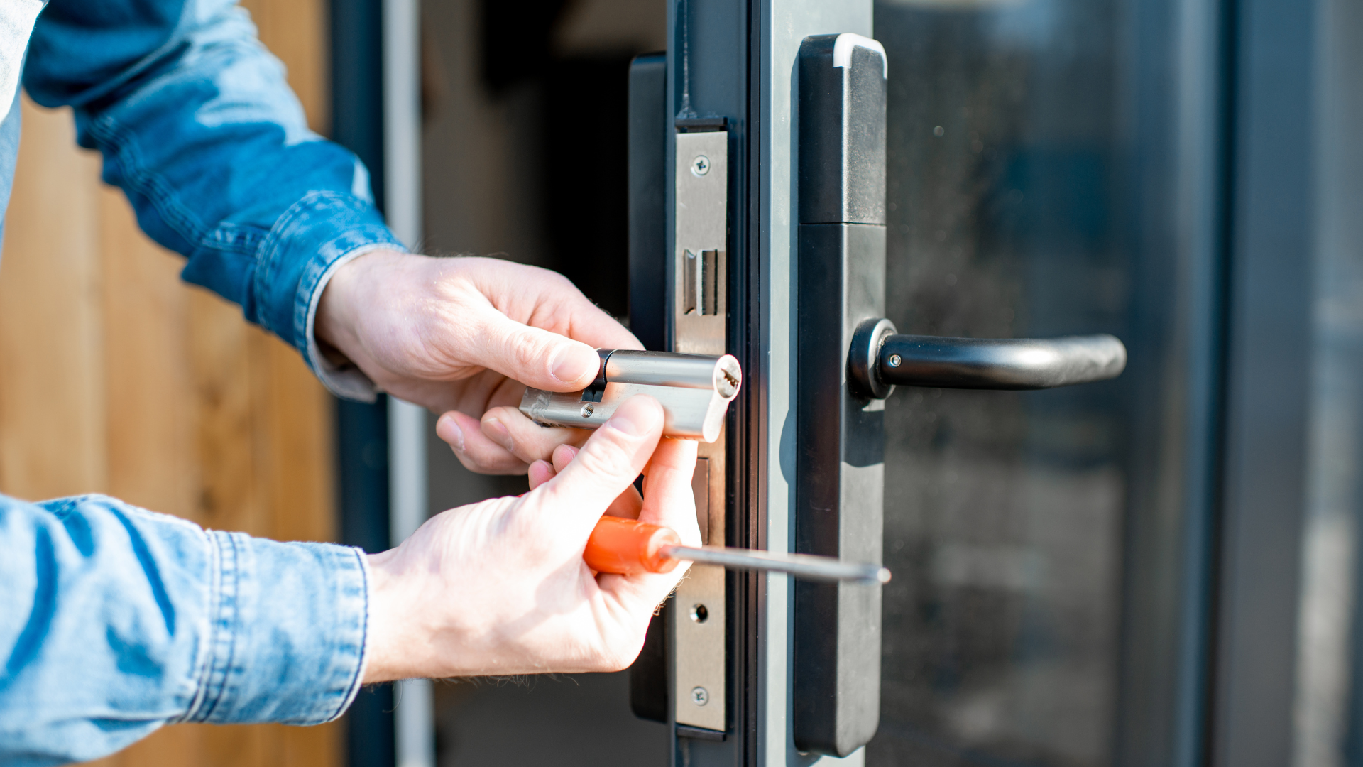 A man is fixing a door lock with a screwdriver.
