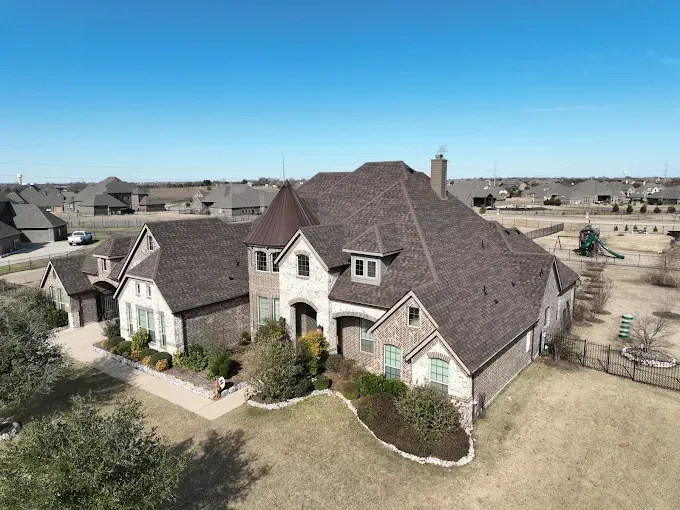 An aerial view of a house with a brown roof and a pool in the backyard.